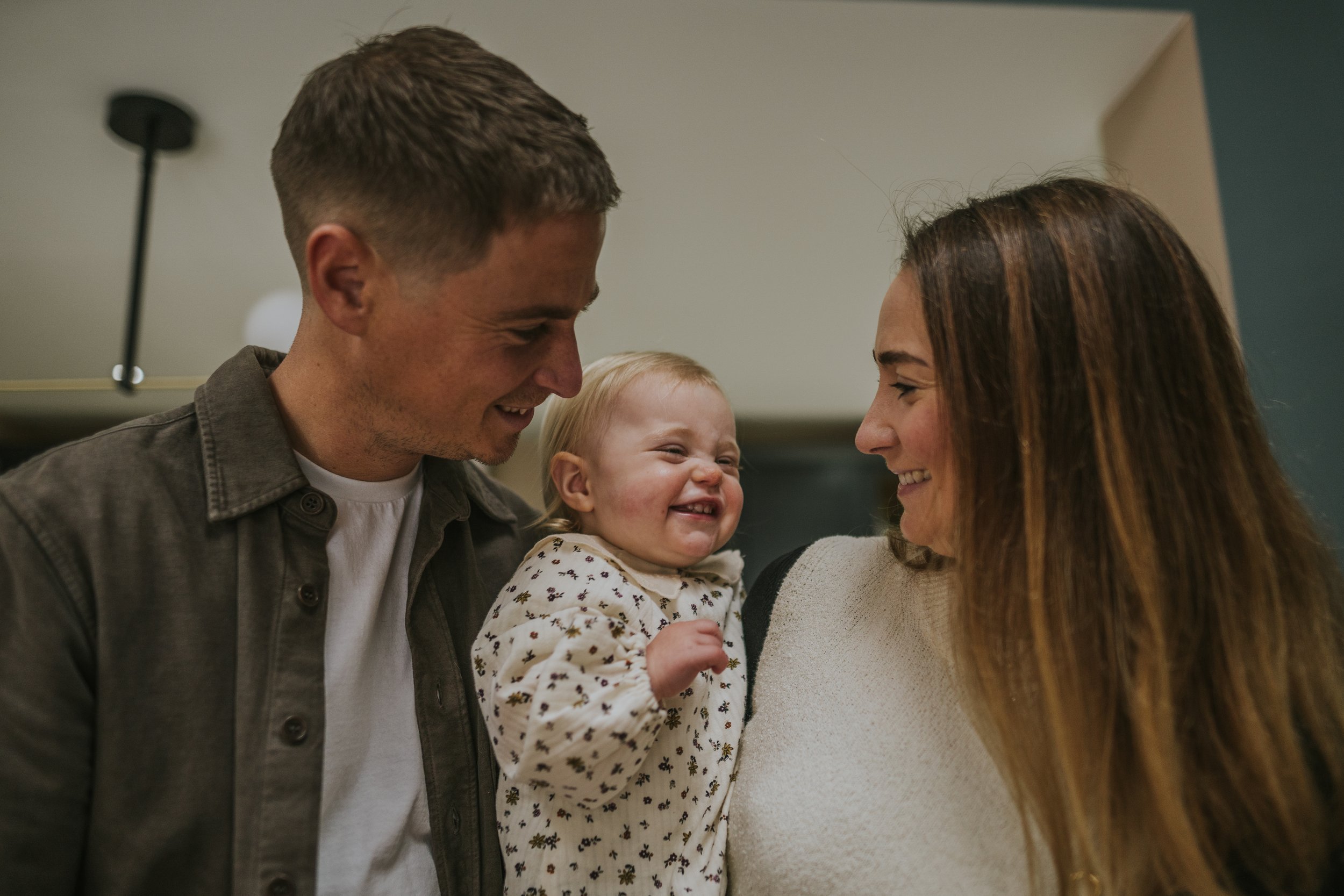 Family Photo of mum, dad and toddler all smiling.
