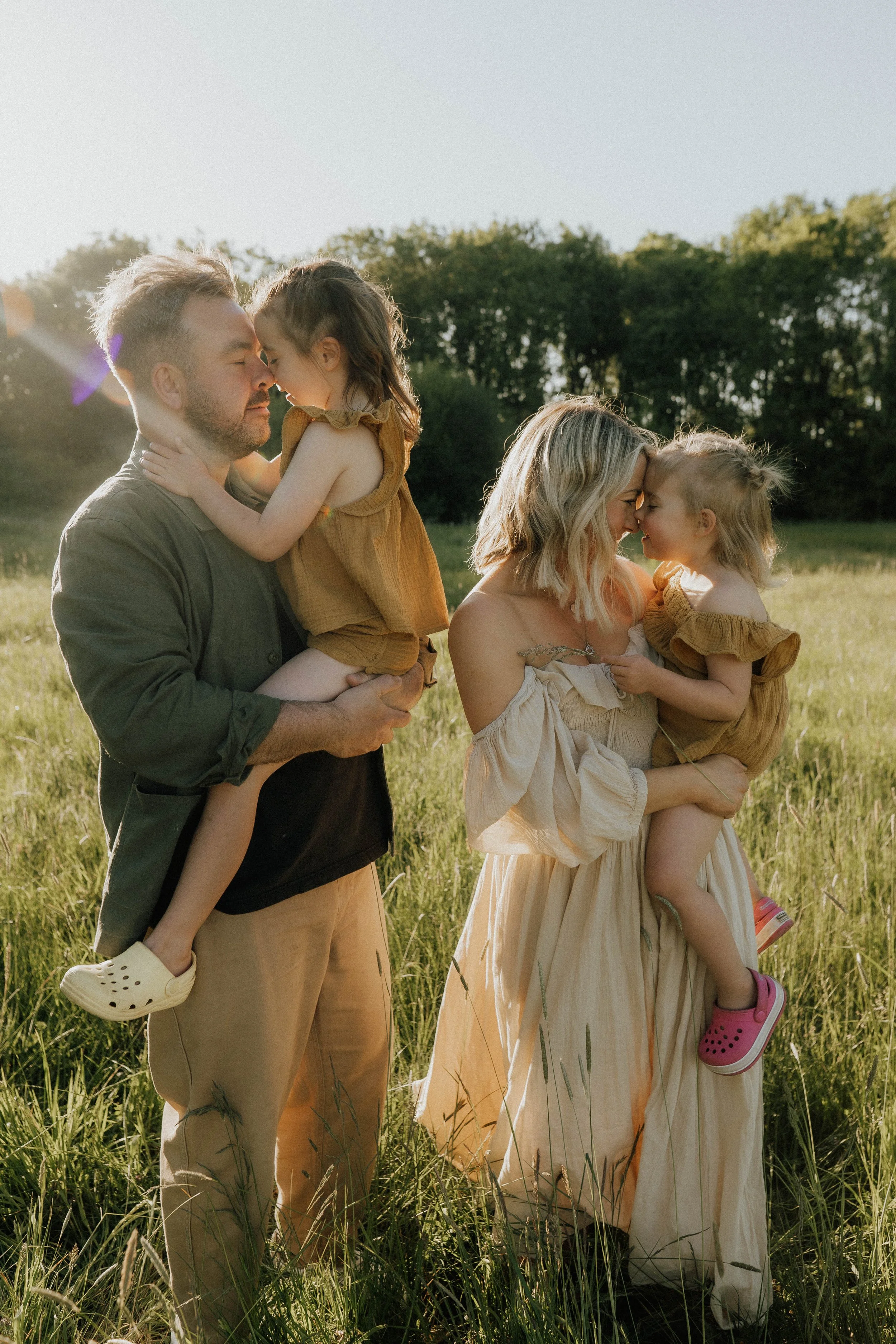 photo of family with two young girls in an evening sunlit meadow in Didsbury on their shoot with Didsbury family photographer Copper + Olive Photo