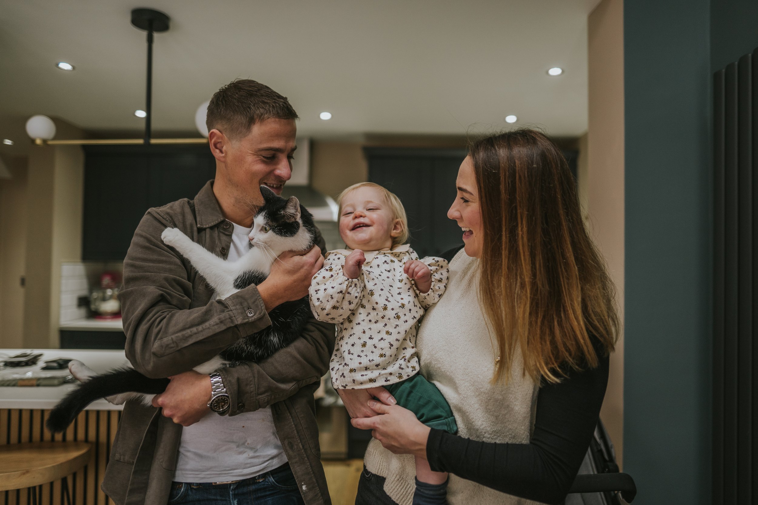 Manchester family photographer's image of a mum, dad, toddler and cat together in their home.