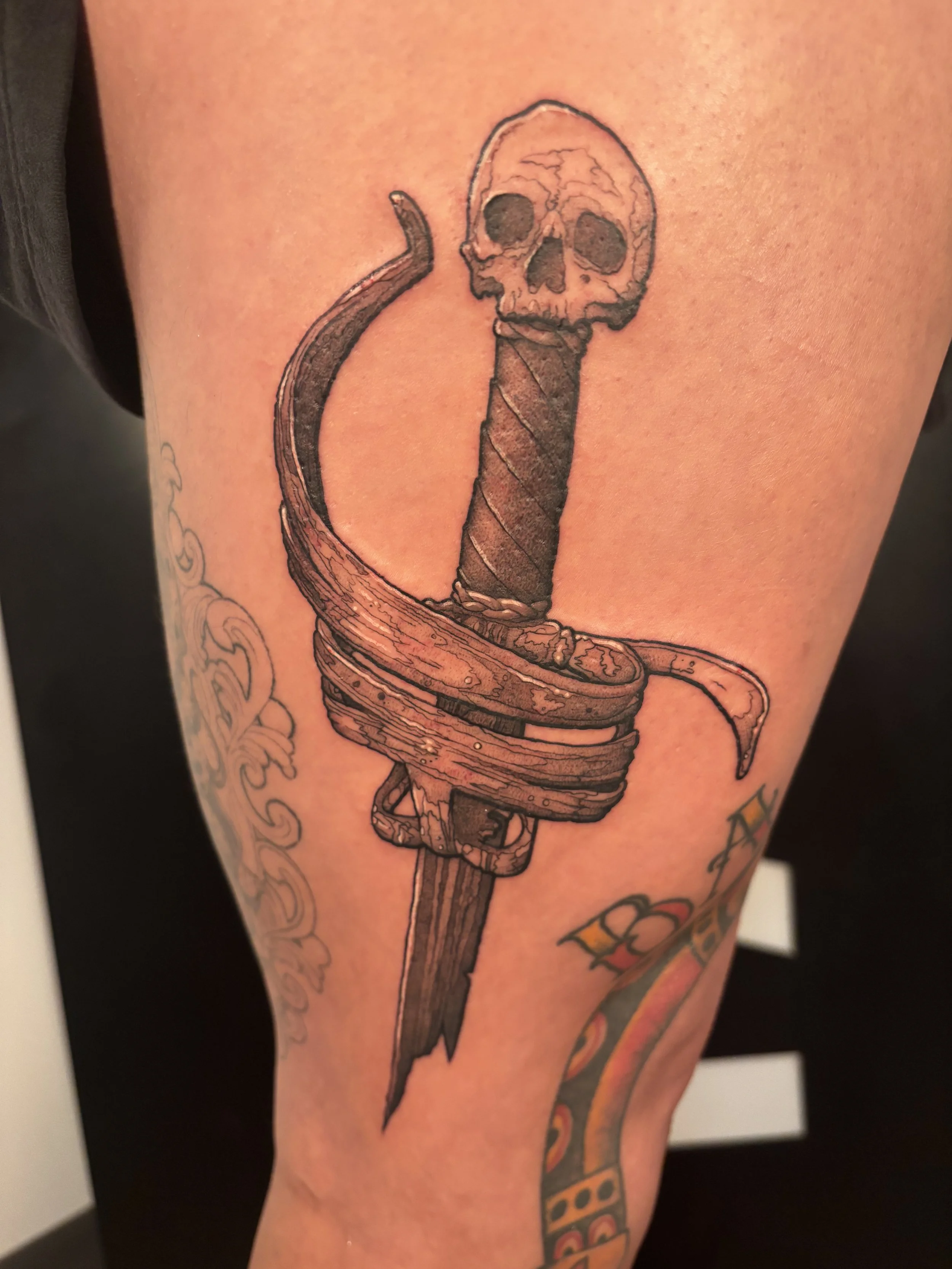 A tattoo of a snake with a skull at the top of its head.