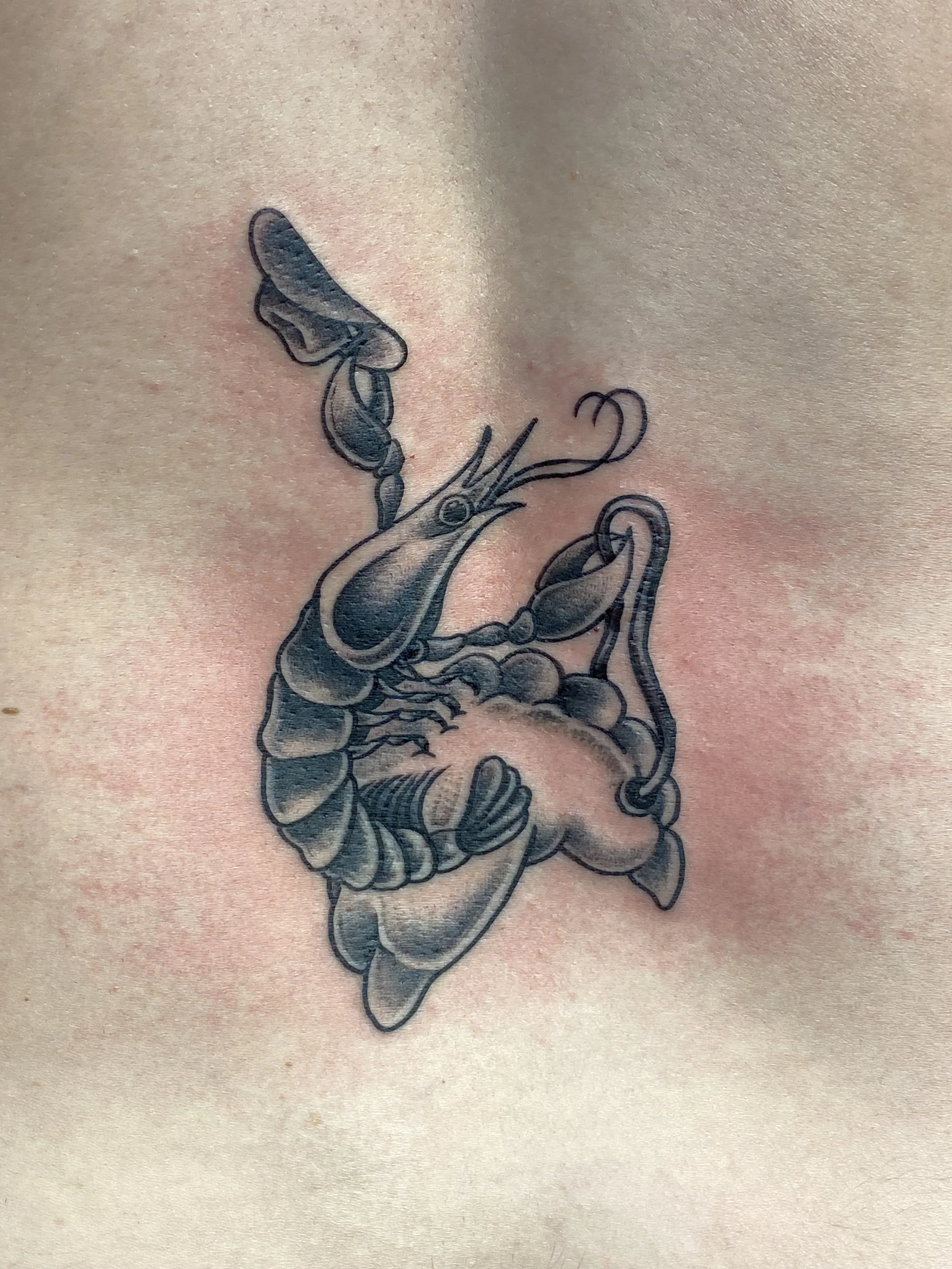 A tattoo of a crab with a bow on its back on a person's skin.