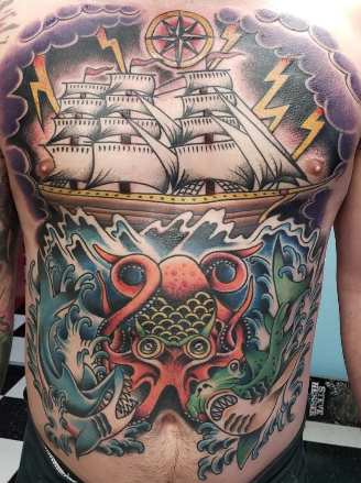Tattoo of a sailing ship above stormy waters with a dragon's head and waves below.
