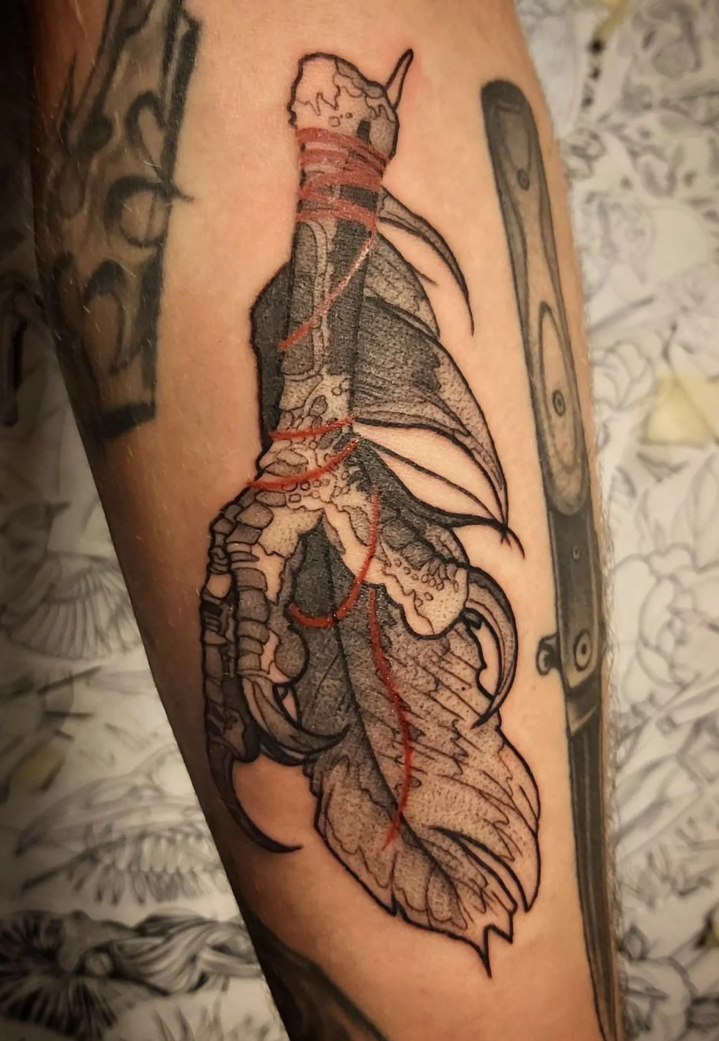 Tattoo of a unicorn with a flowing mane, detailed with black ink and red accents, on a person's arm.