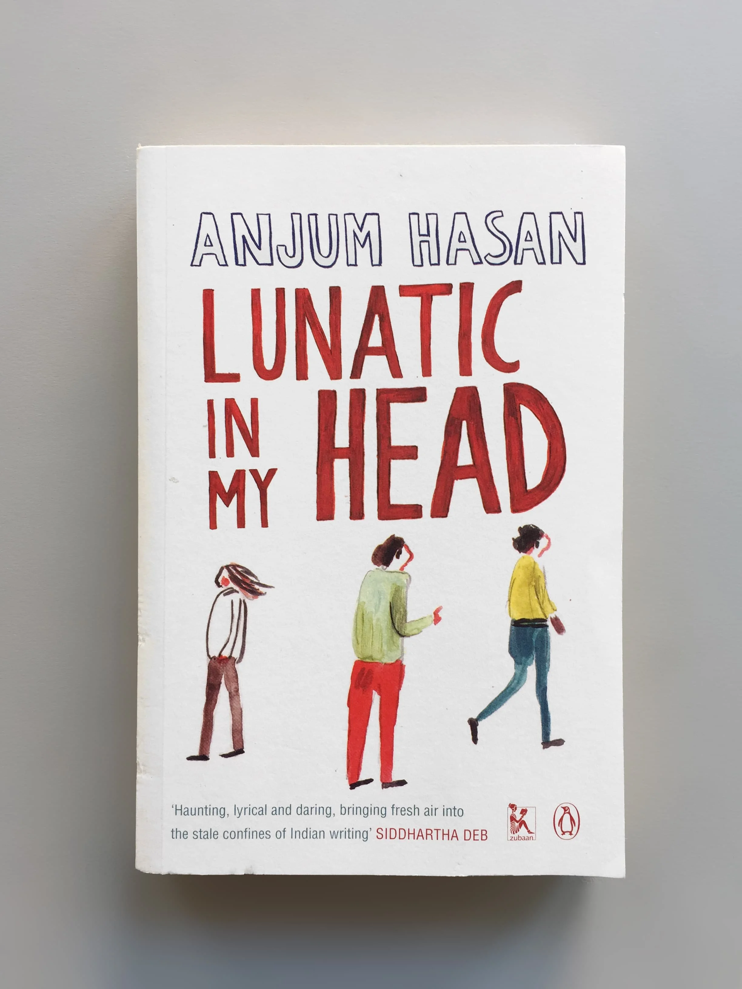 Cover of the book 'Lunatic In My Head' by Anjum Hasan, featuring illustrated figures and a quote praising the book at the bottom. Published by Zubaan and Penguin.