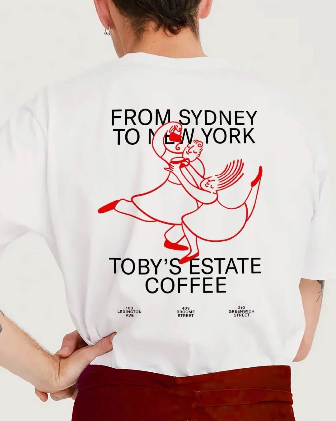 A tshirt design for Tobys Estate Coffee with illustration of 2 characters illustrated by Debora Szpilman dancing together with a coffee cup.