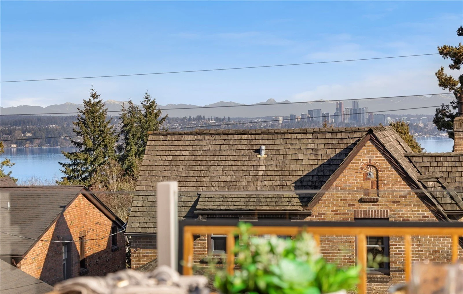 View of rooftops, a lake, city skyline, and distant mountains on a clear day.