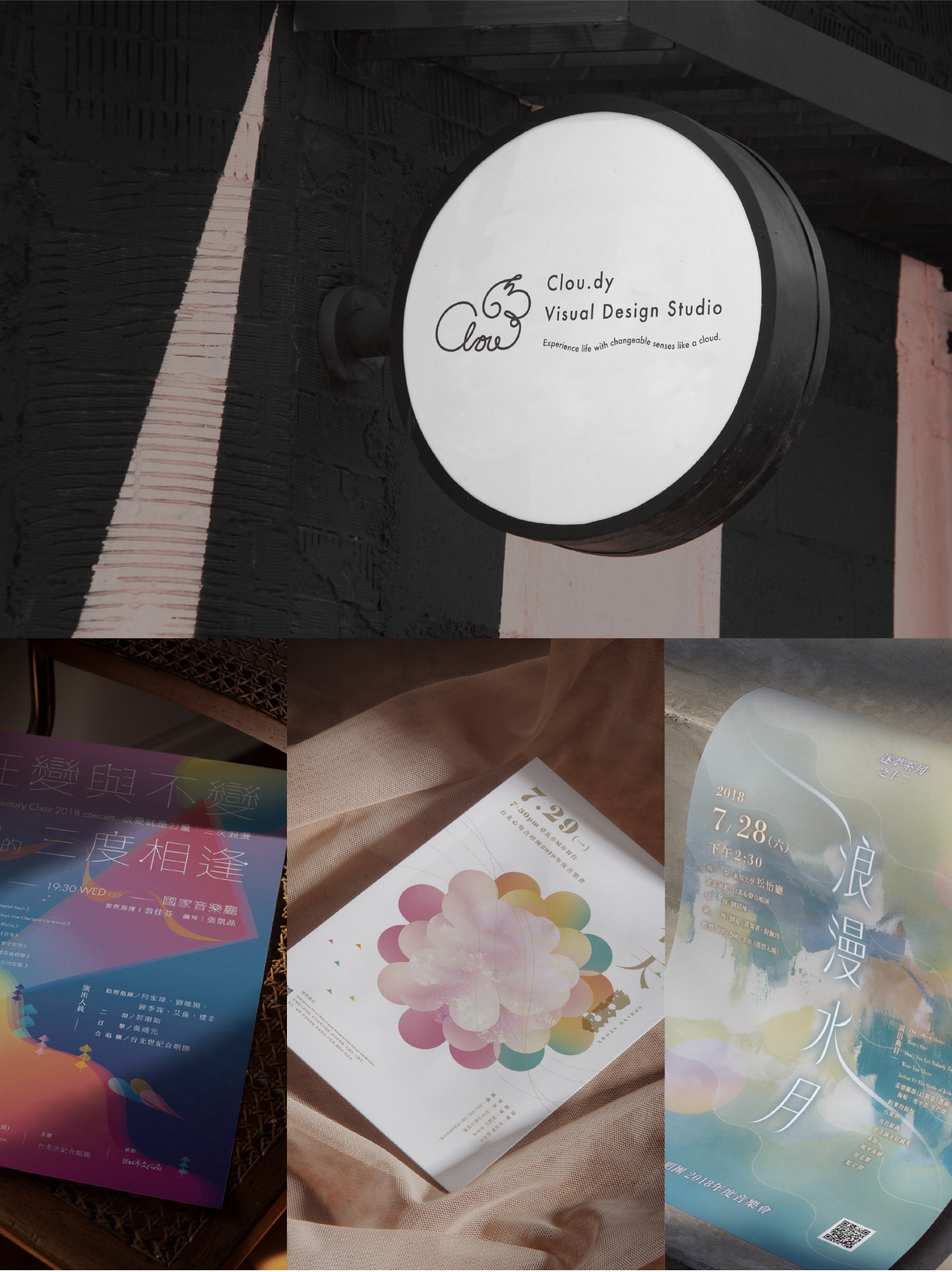 Sign for Clou.dy Visual Design Studio mounted on a black textured wall, with three colorful brochures or flyers spread out on a surface below it.