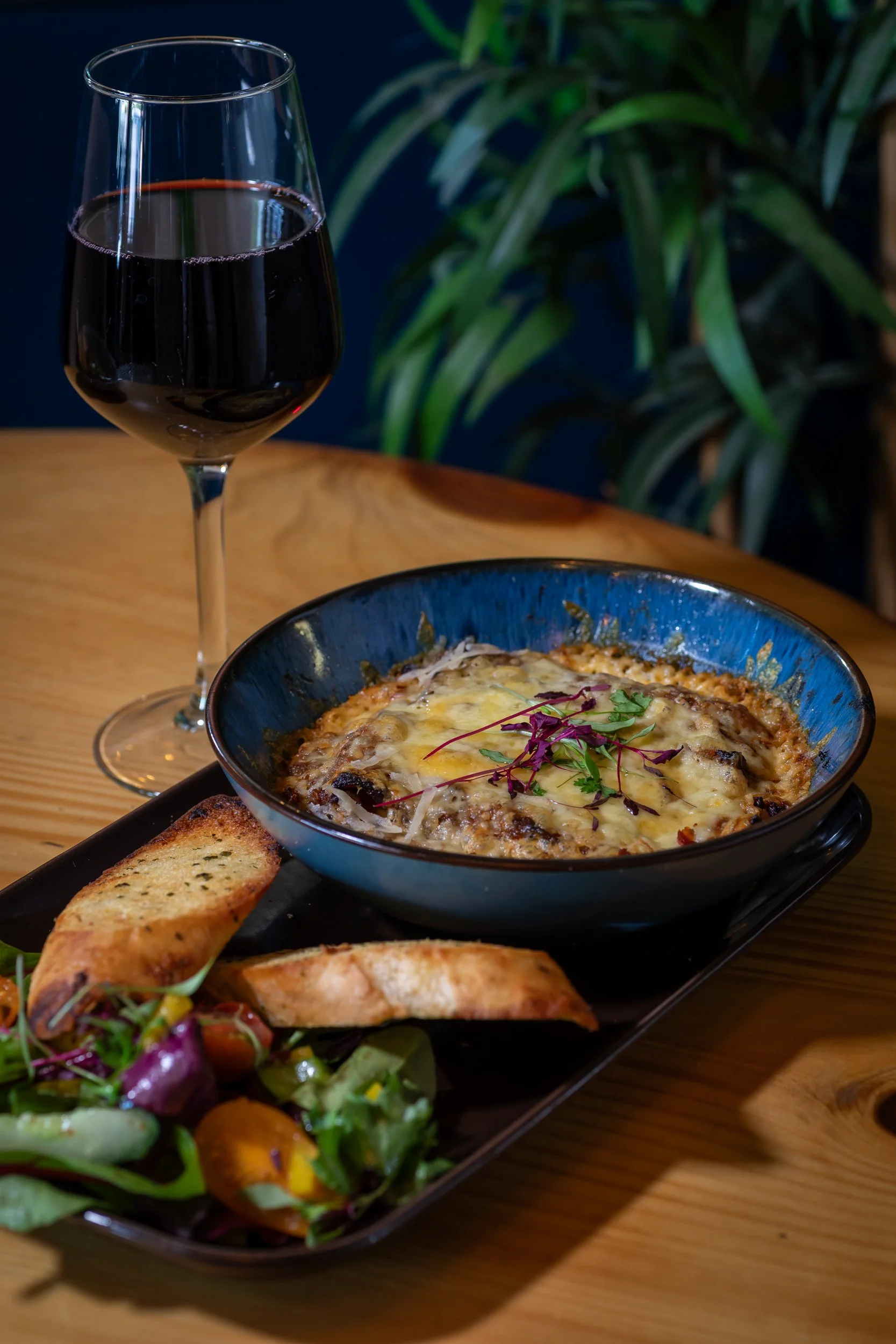 Beef lasagne with glass of read wine at The Folly Wine Bar in Petersfield, Hampshire. Food photography by Sequoia Studios.