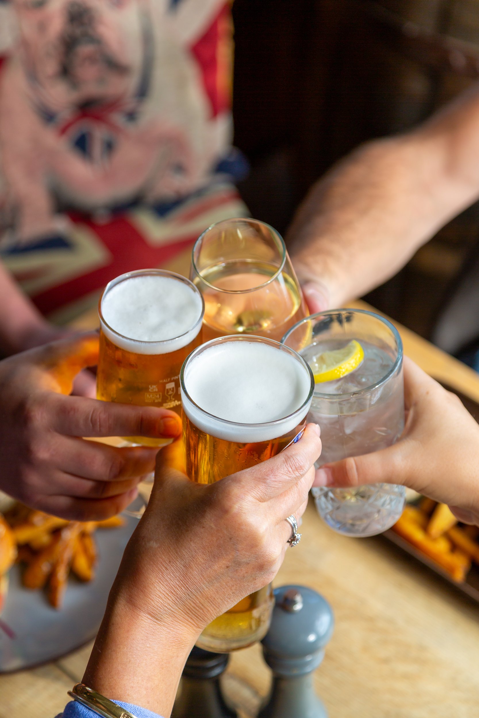 Four customers clinking glasses at The Folly Lunch Club in Petersfield, Hampshire. Lifestyle photography by Sequoia Studios.