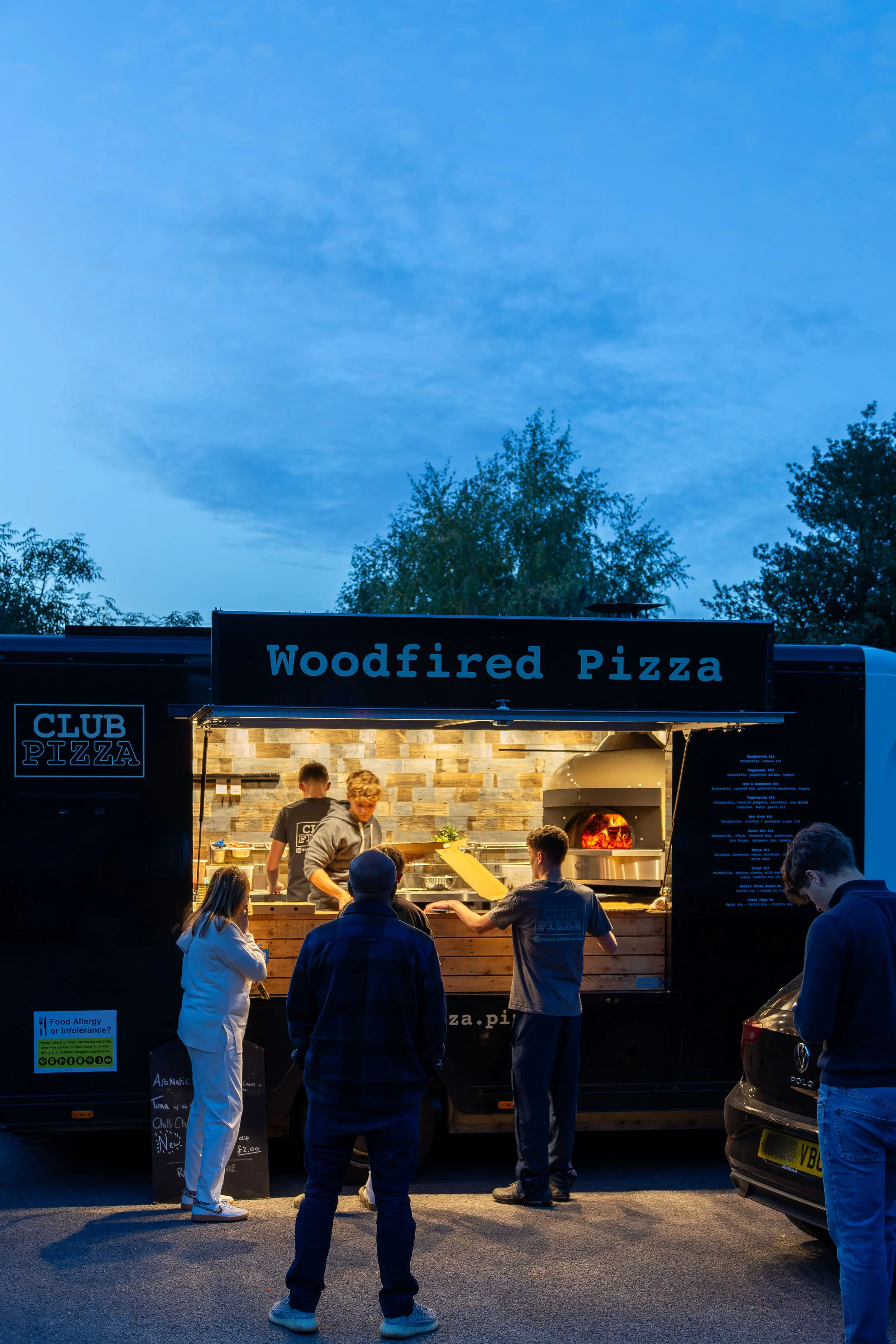 Customers waiting patiently as dusk falls at Club Pizza van