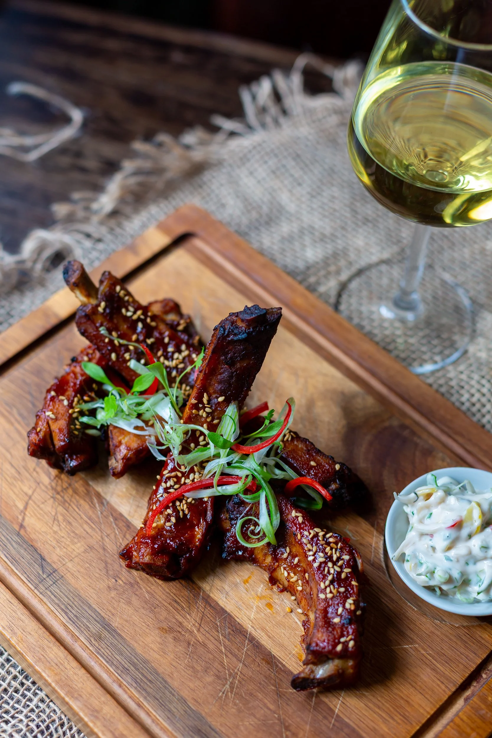 Portrait photo of Korean-style pork ribs paired with white wine at The Wheatsheaf Inn Grayswood, Surrey – Food Photography by Sequoia Studios