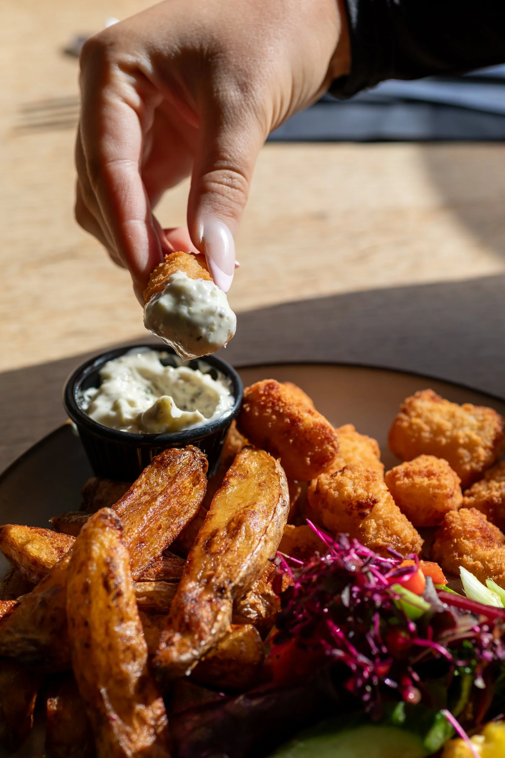 Female hand dips scampi portion into tartare sauce at The Folly Wine Bar in Petersfield, Hampshire. Food photography by Sequoia Studios.