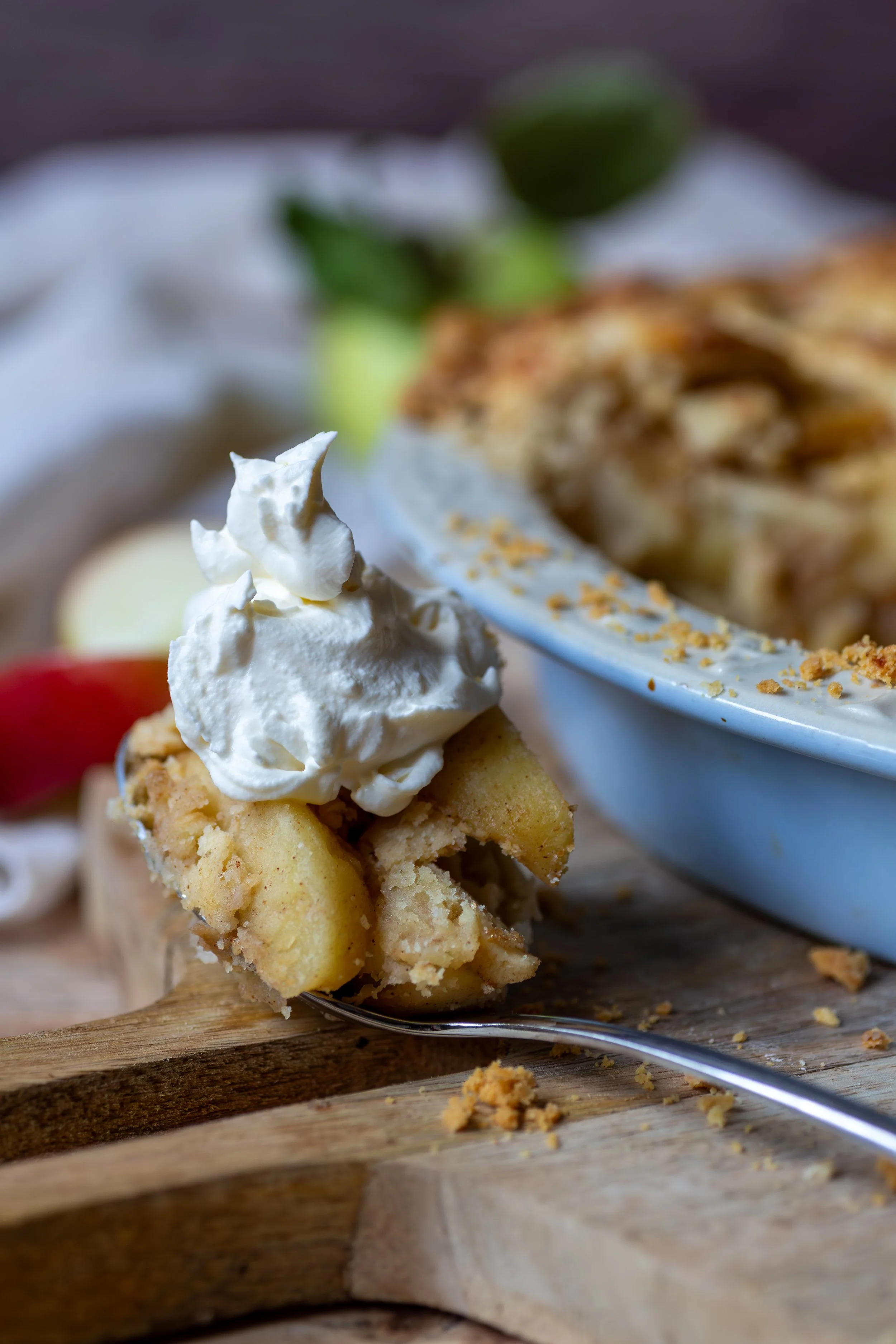 Whipped cream on top of a spoonful of fresh homemade apple pie