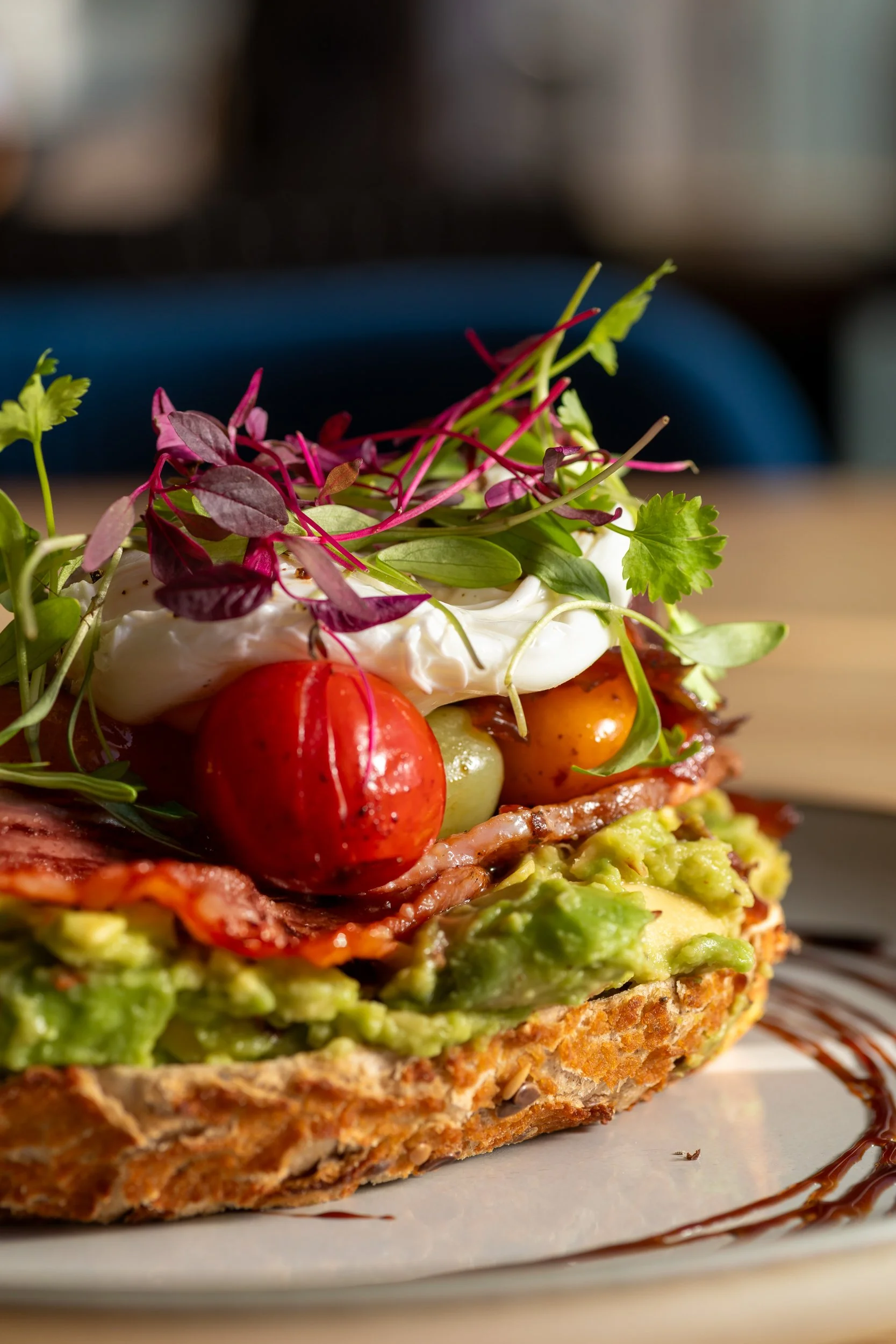 Close up of smashed avocado on sourdough with bacon & poached egg at The Folly Wine Bar in Petersfield, Hampshire. Food photography by Sequoia Studios.