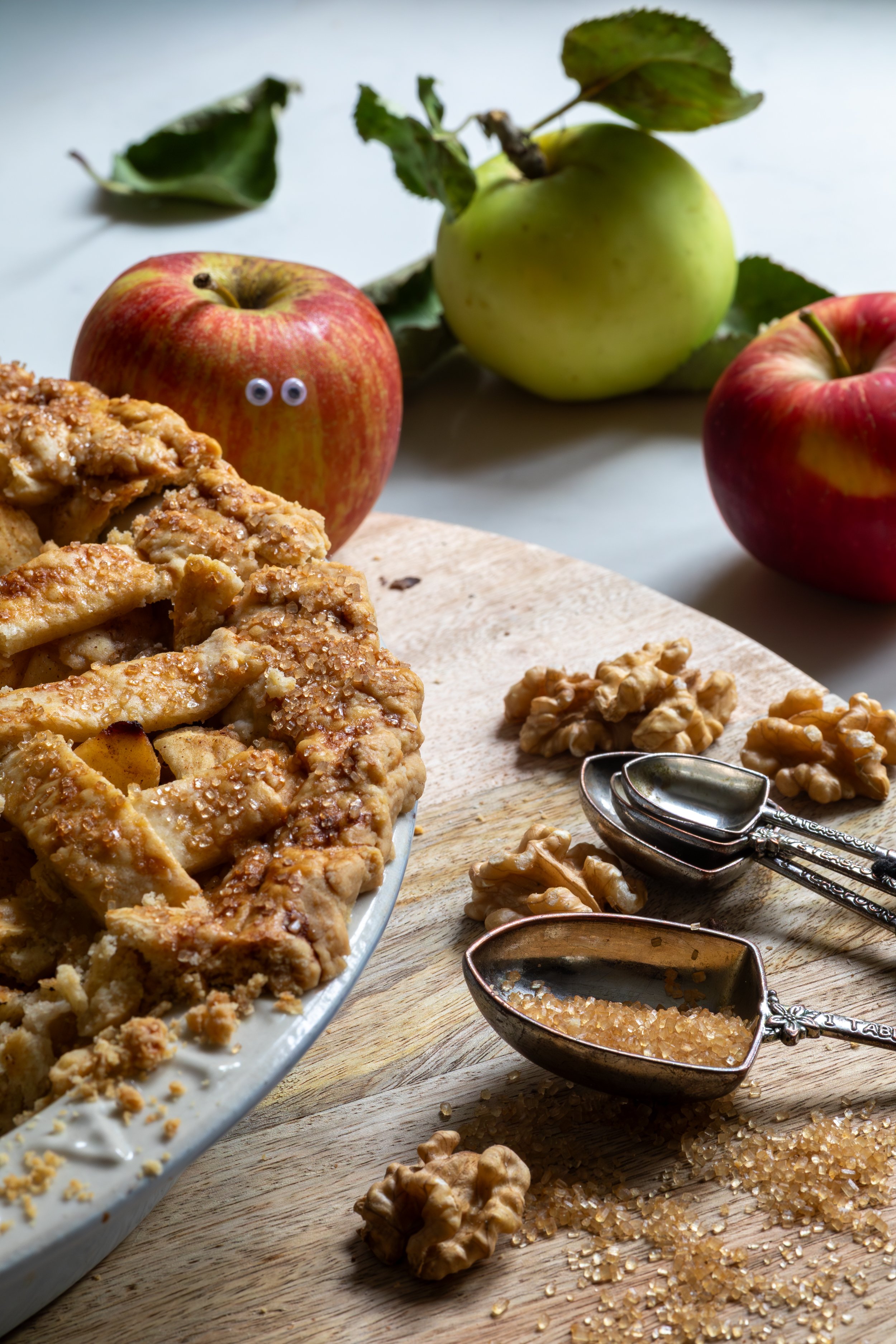 Homemade apple pie with cheeky googly-eyed apple peaking from behind the dish