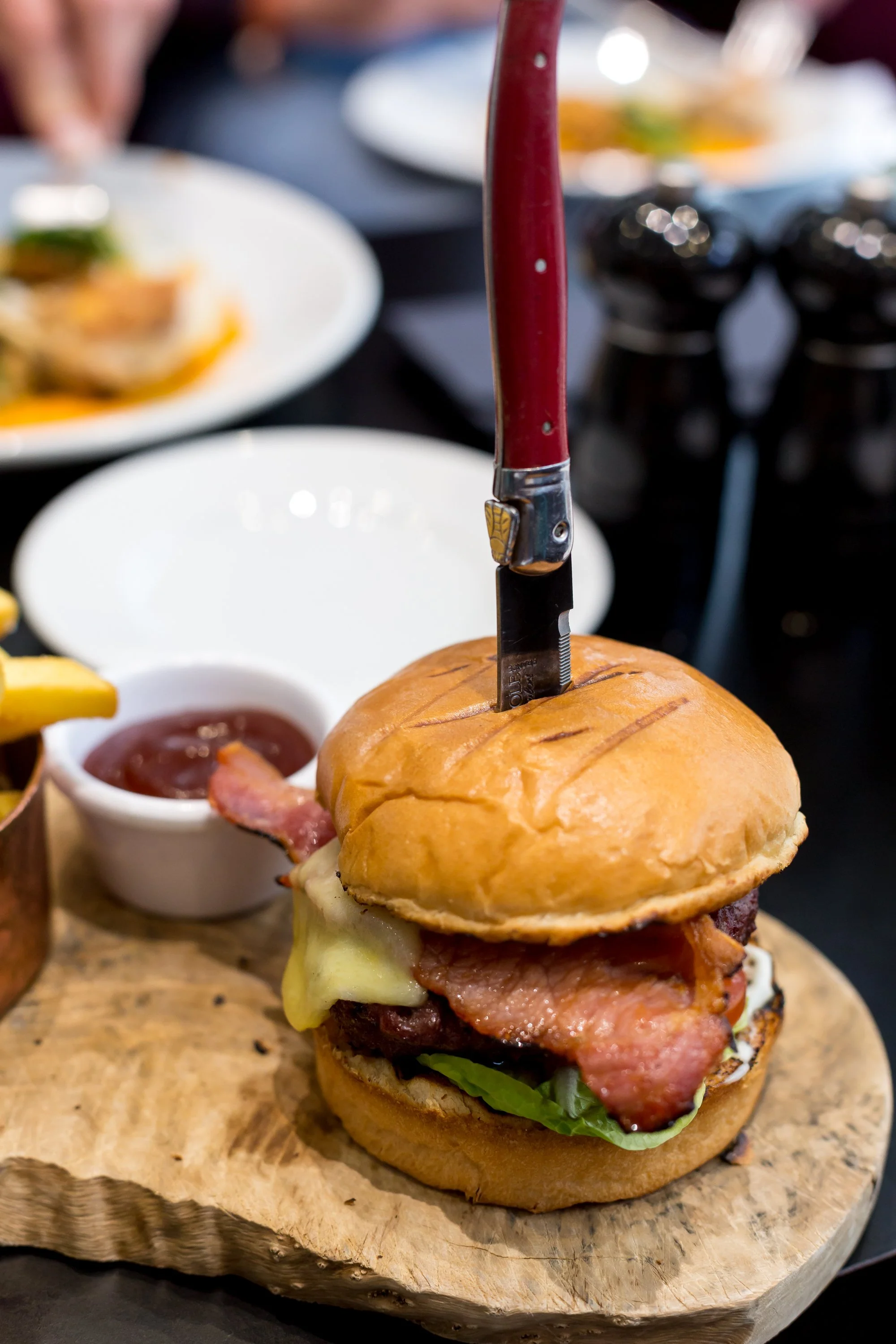 Cheese and bacon burger with knife stabbed through it