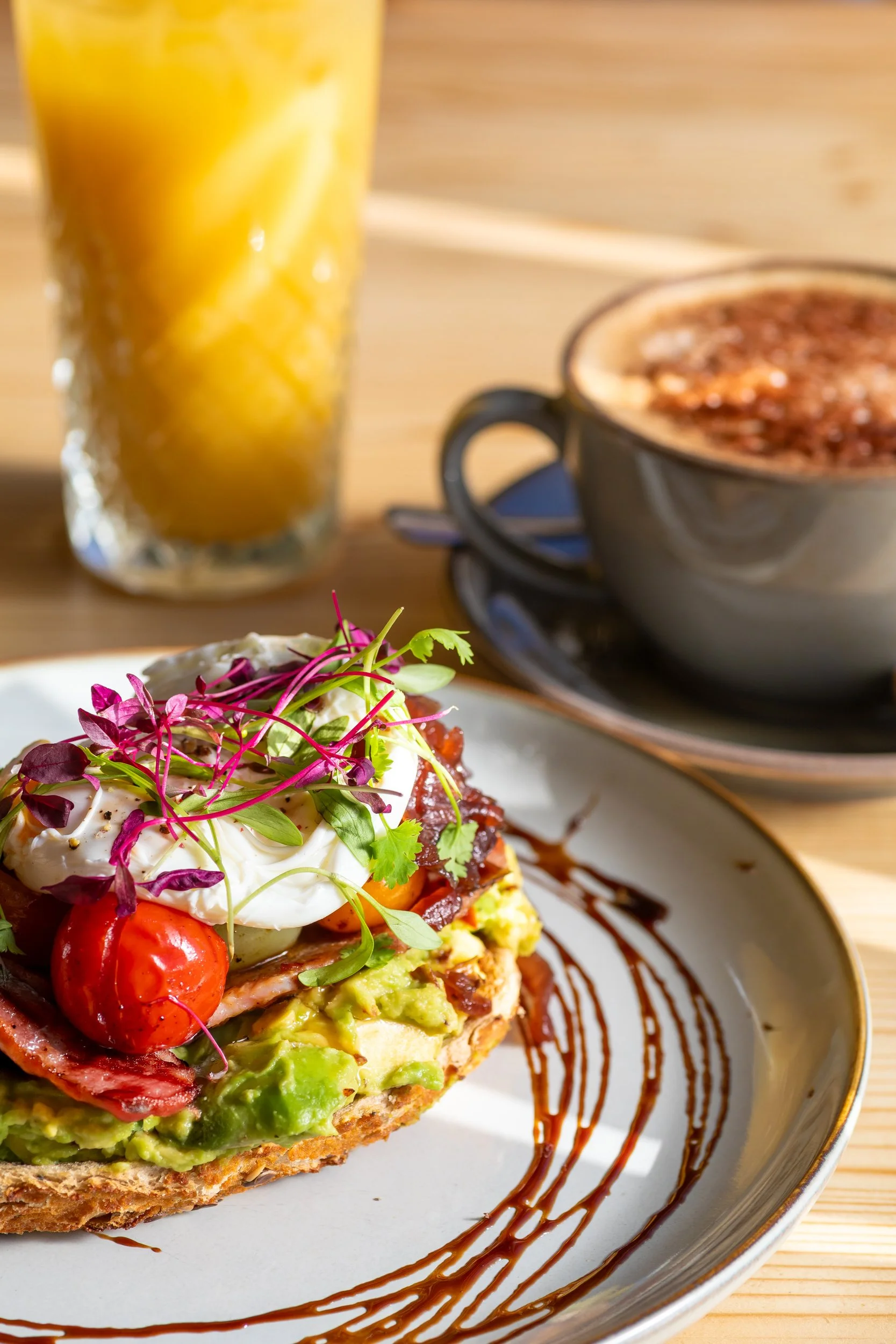 Smashed avocado on sourdough with poached egg, orange juice and cappuccino coffee at The Folly Wine Bar in Petersfield, Hampshire. Food photography by Sequoia Studios.
