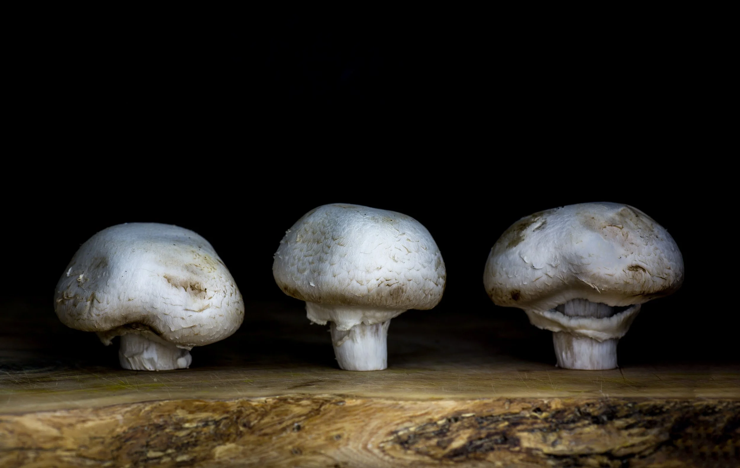 three-organic-button-mushrooms-on-wooden-board.jpg