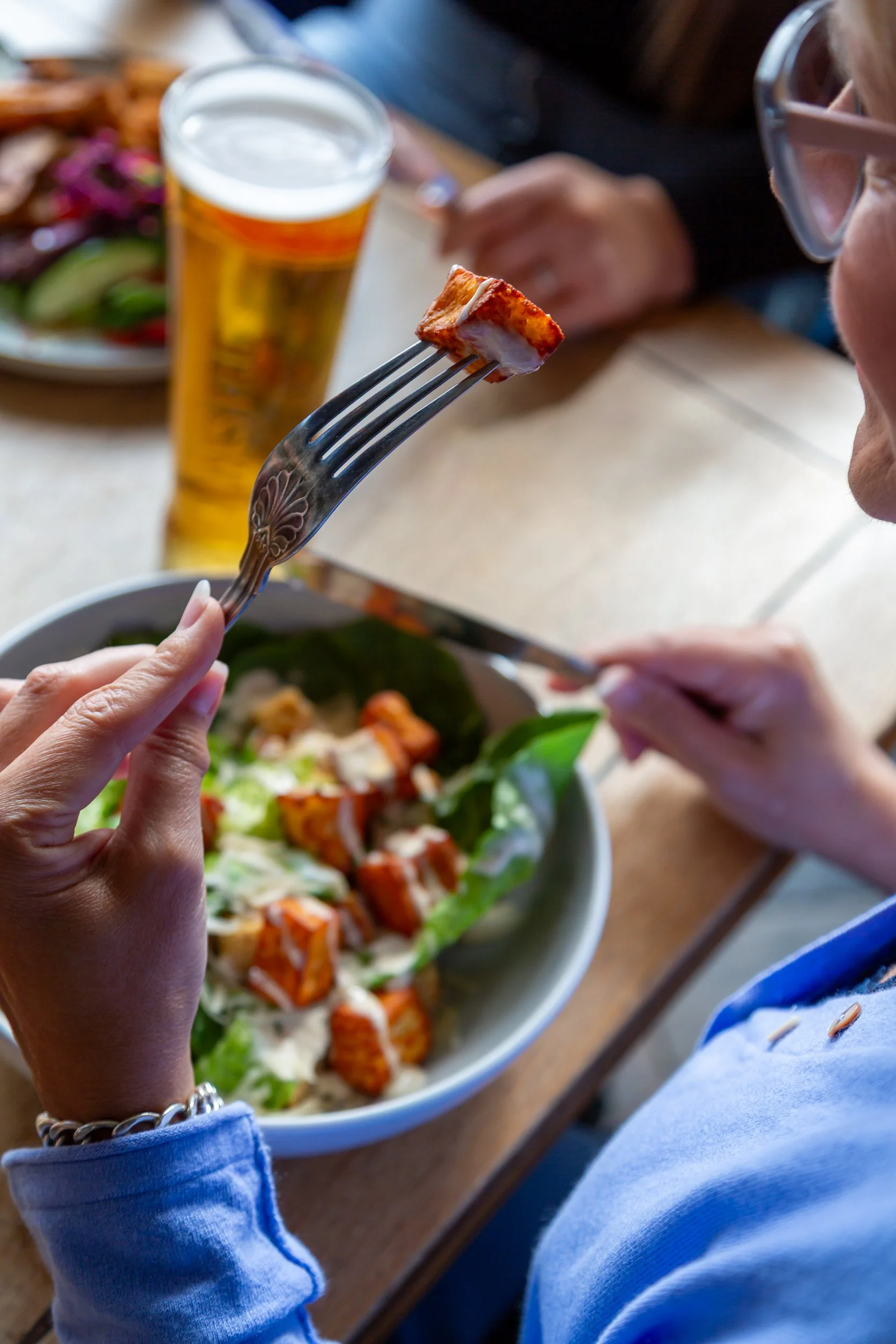 Lady enjoying halloumi caesar salad at The Folly Wine Bar in Petersfield, Hampshire. Lifestyle photography by Sequoia Studios.