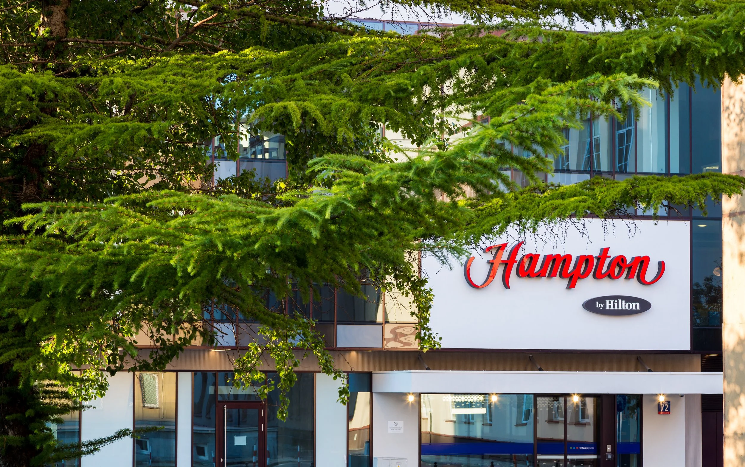 Close crop of the entrance of the Hampton by Hilton hotel in Warsaw, Poland with attractive fir tree