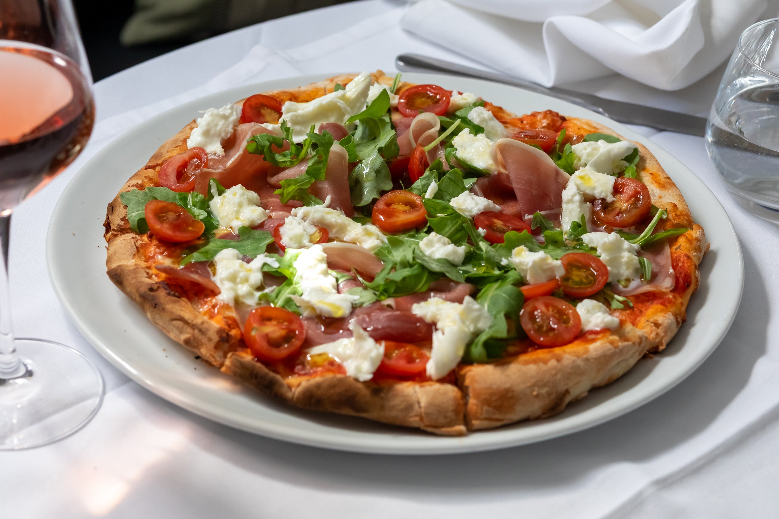 Fresh bufalina pizza with parma ham, cherry tomatoes and rocket at Carlo Italian Petersfield