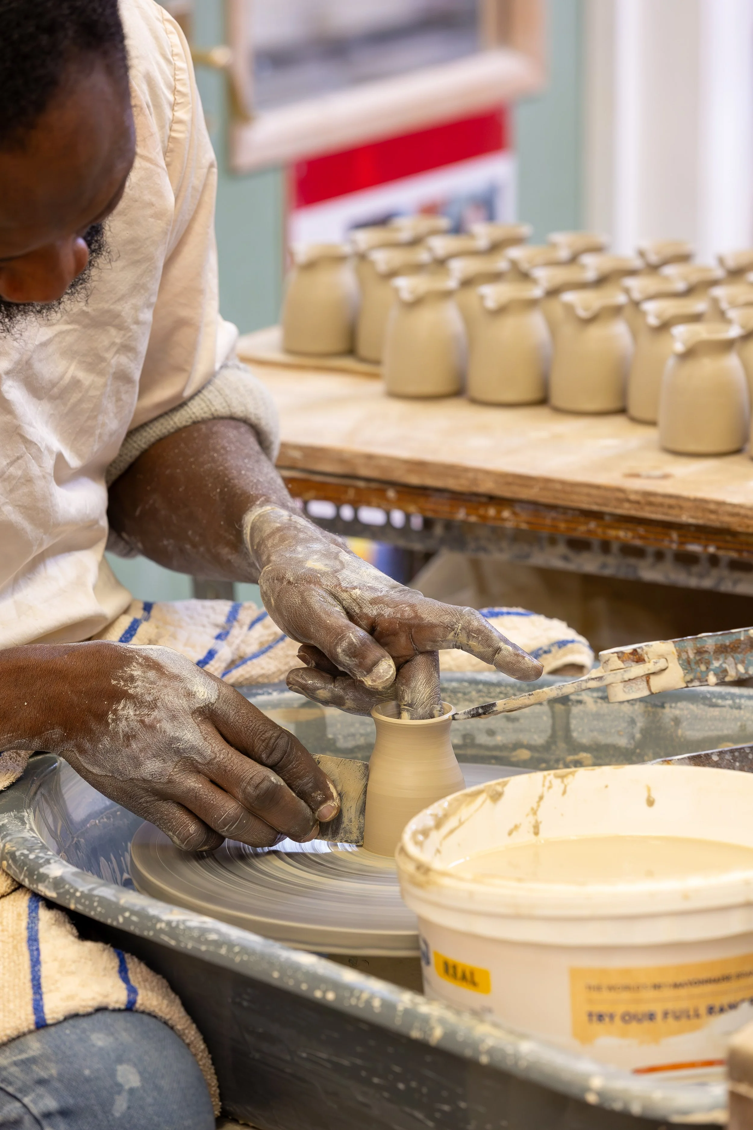 Potter at his wheel crafting a milk jug at Grayshott Pottery
