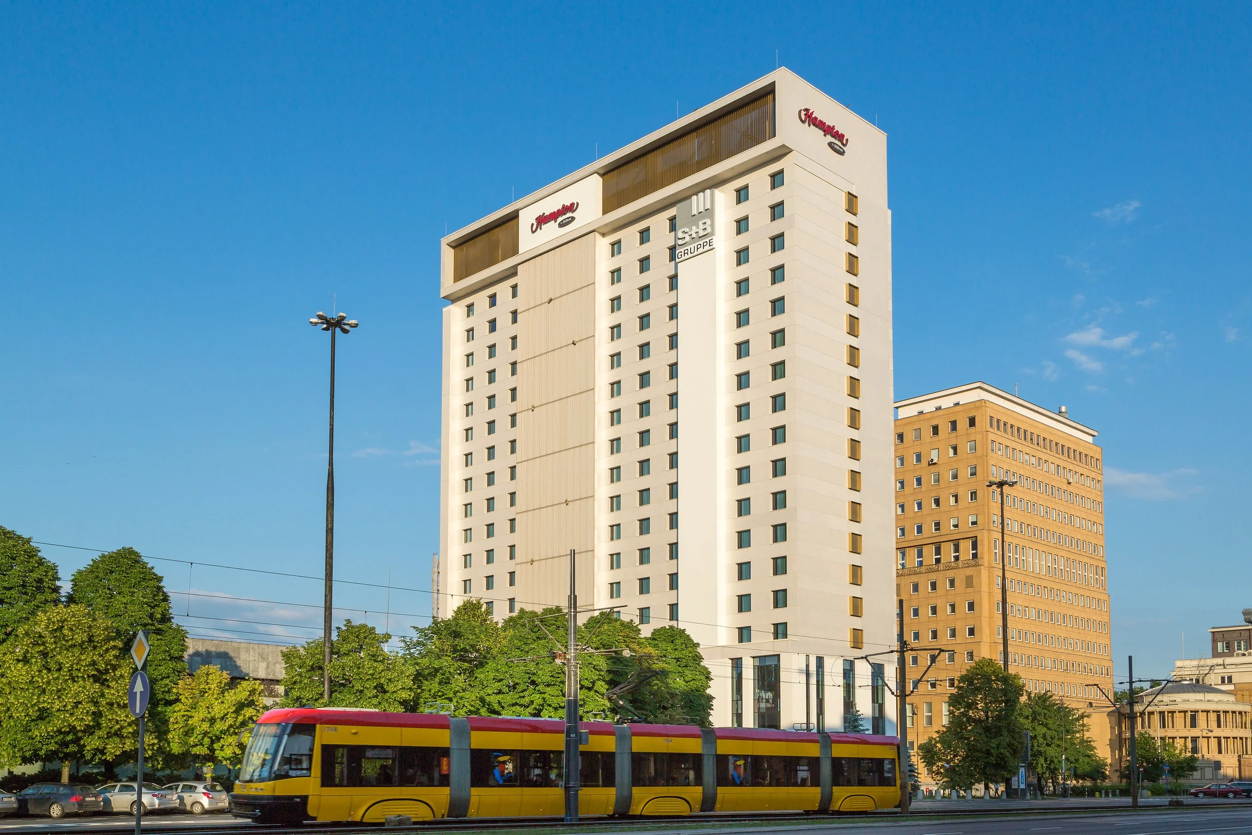 Daytime exterior of Hampton by Hilton hotel in Warsaw, Poland with the local tram passing by in the foreground