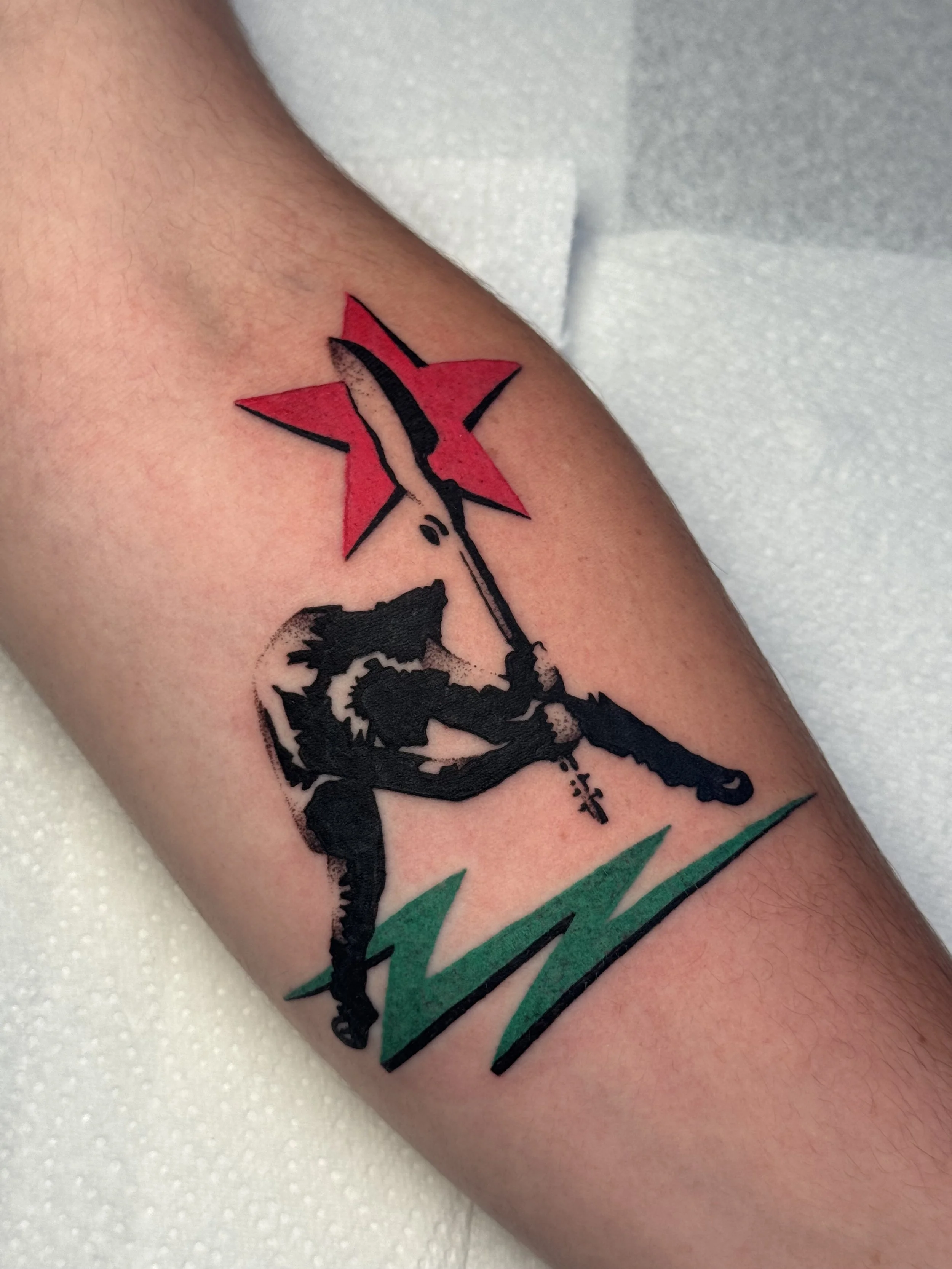 Tattoo of man holding a guitar, based off of the Clash's album London Calling using the pink and green colours from the album cover.