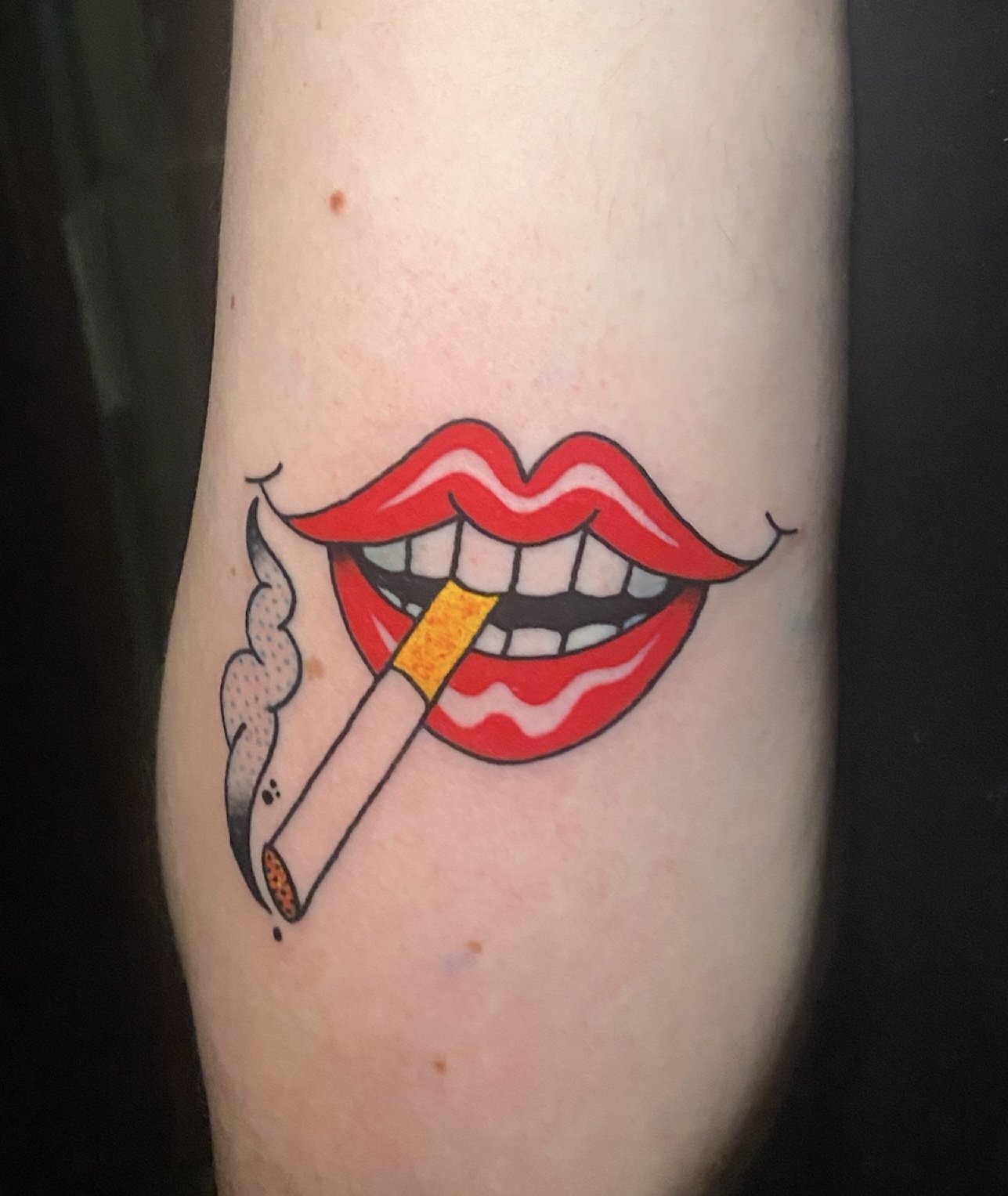 Tattoo of red lips holding a lit cigarette with smoke.