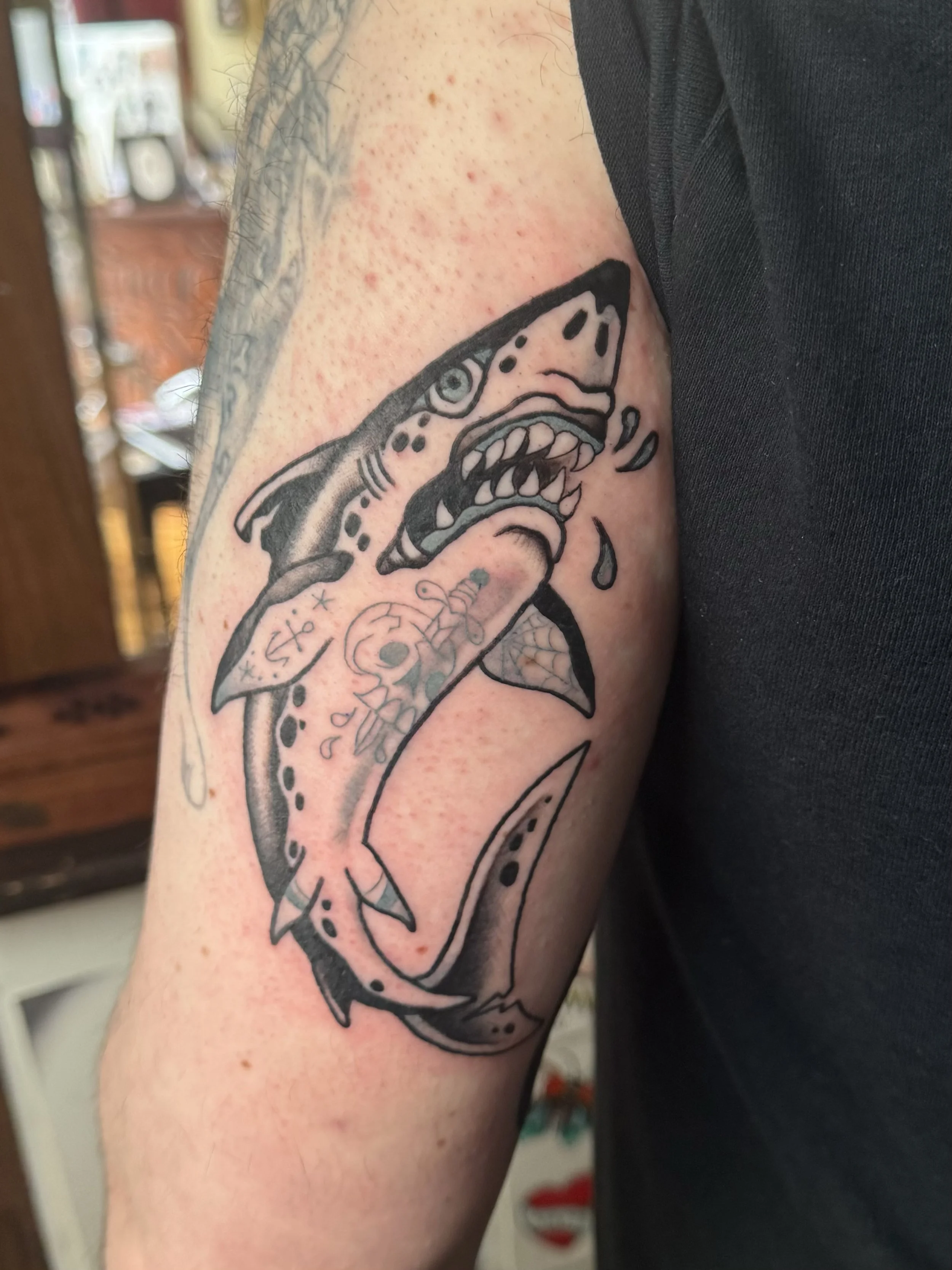 Tattoo of a fierce shark with sharp teeth and tattoos on the arm.