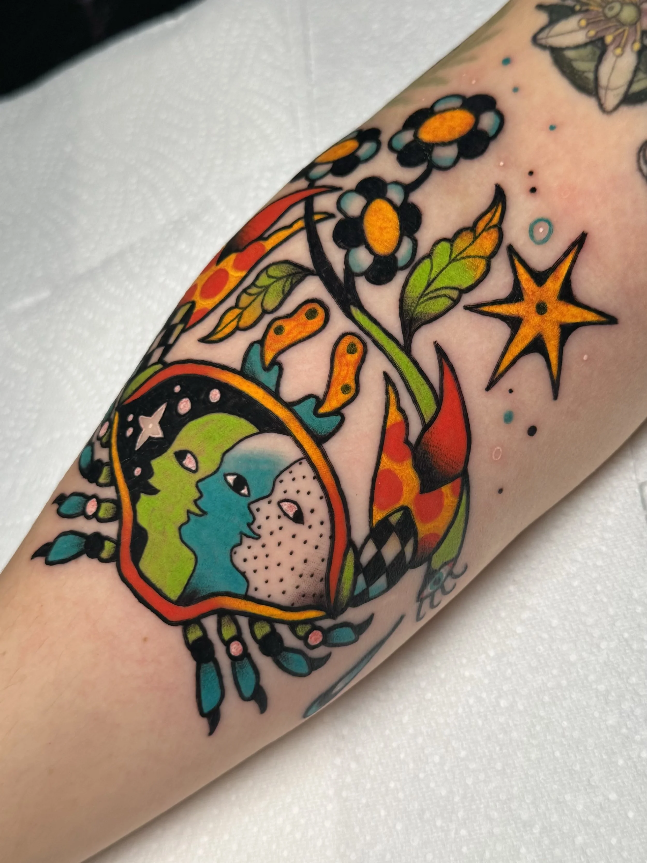 A colorful tattoo featuring a traditional style crab leaves, and decorative patterns.