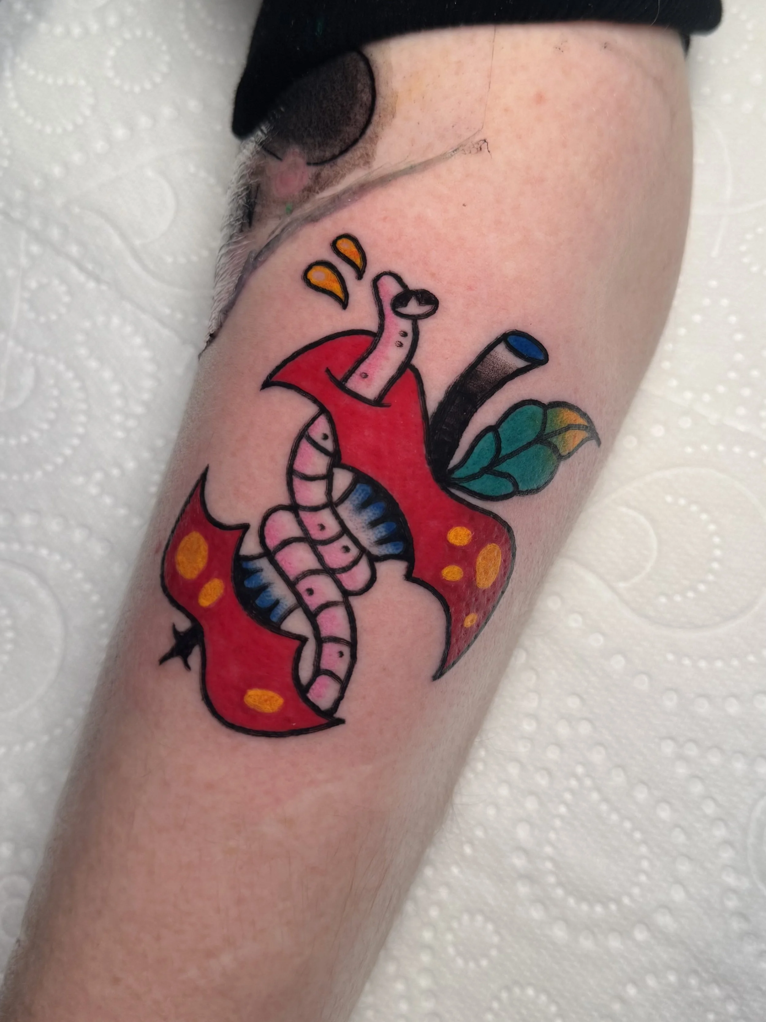 Colorful tattoo of an apple with a worm peaking out of it.