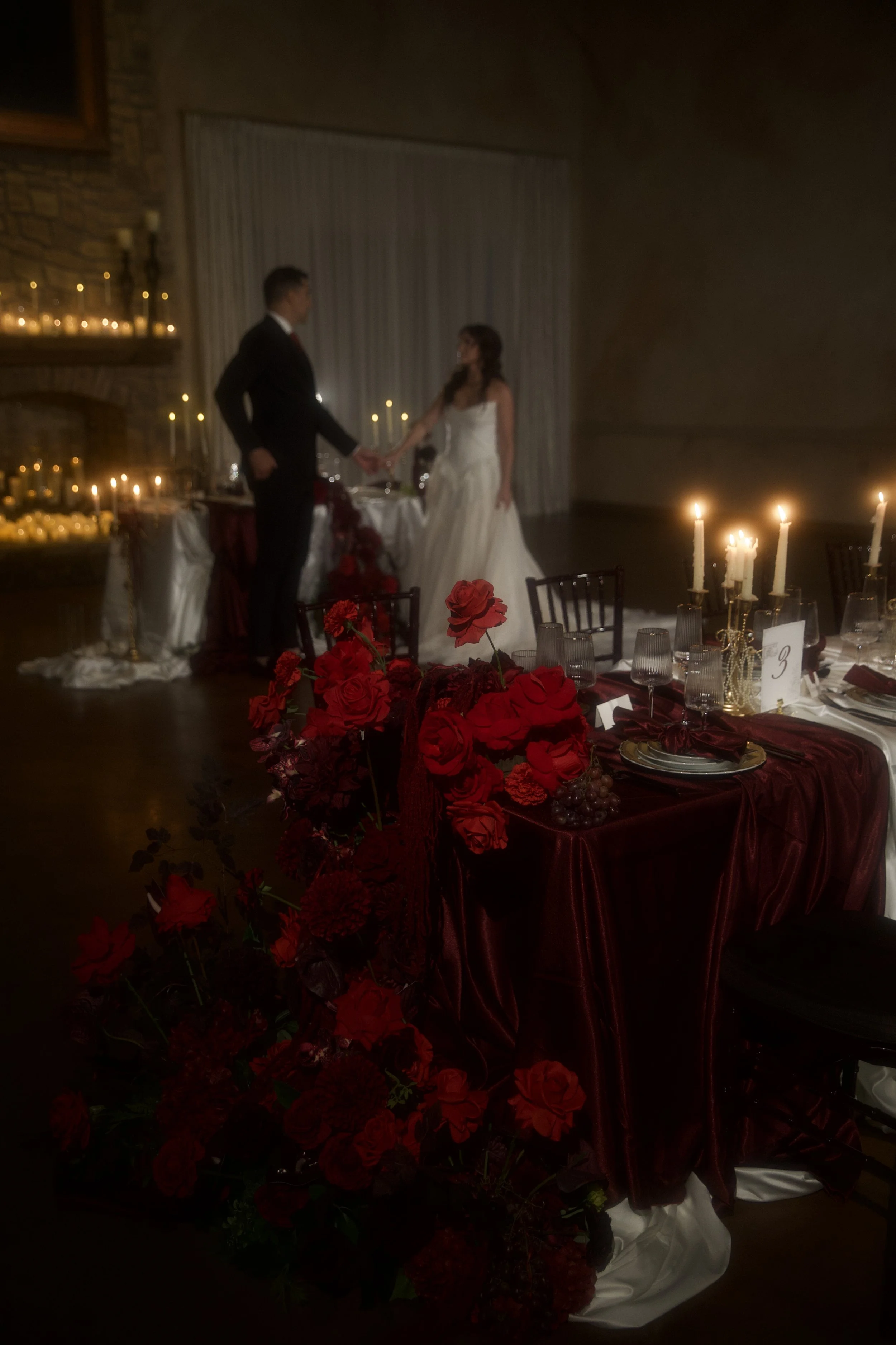 A dramatic  floral installation featuring deep red roses, burgundy blooms, cascading amaranthus, and layered candlelight. Designed by S.R. Event Design & Decor for a dark romance styled shoot at Bella Sera Event Villa near Pittsburgh, this statement 