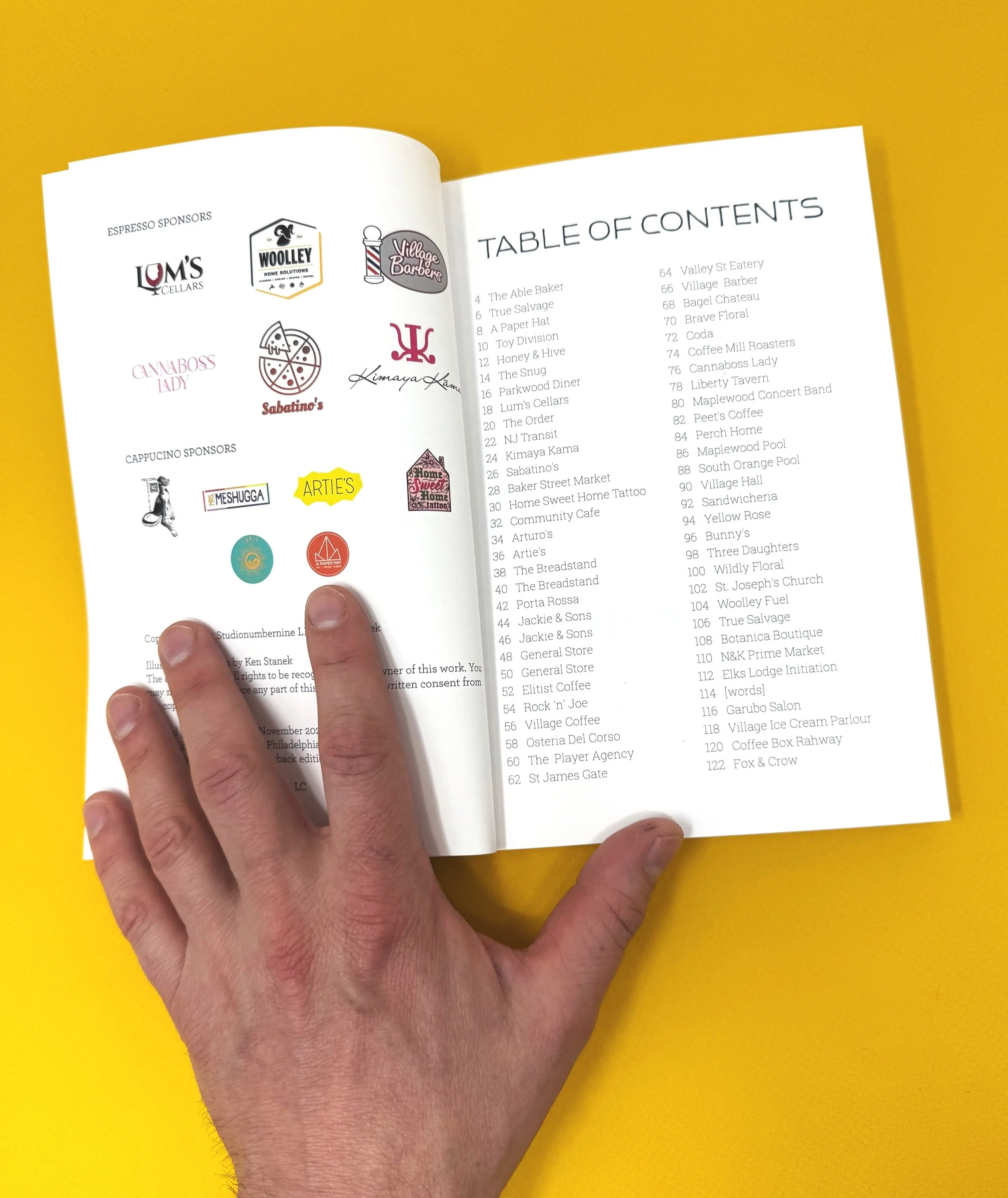 Open booklet with sponsorship logos on left page and table of contents on right page, against a yellow background.