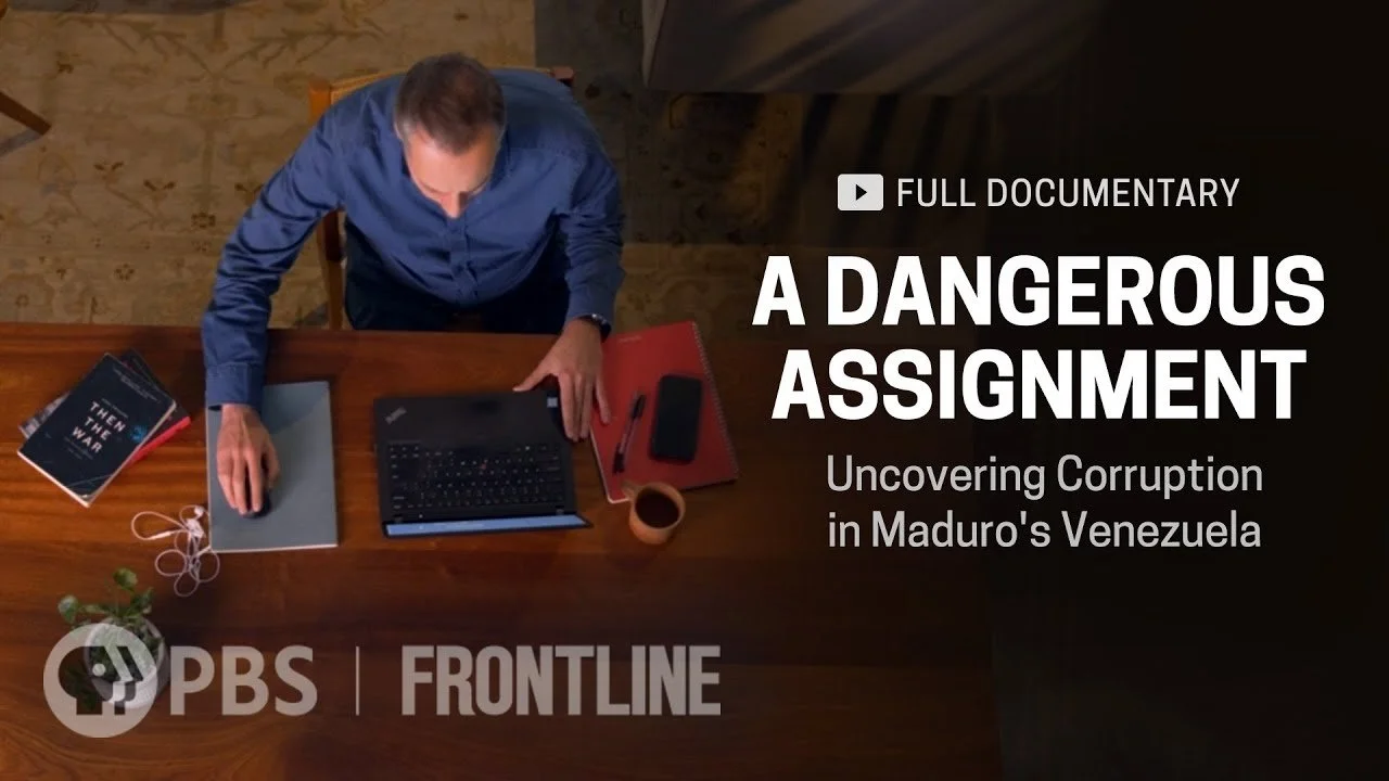 Overhead view of a man sitting at a wooden desk with a laptop, book, notebook, coffee cup, and phone, promoting a PBS documentary titled 'A Dangerous Assignment: Uncovering Corruption in Maduro's Venezuela'.