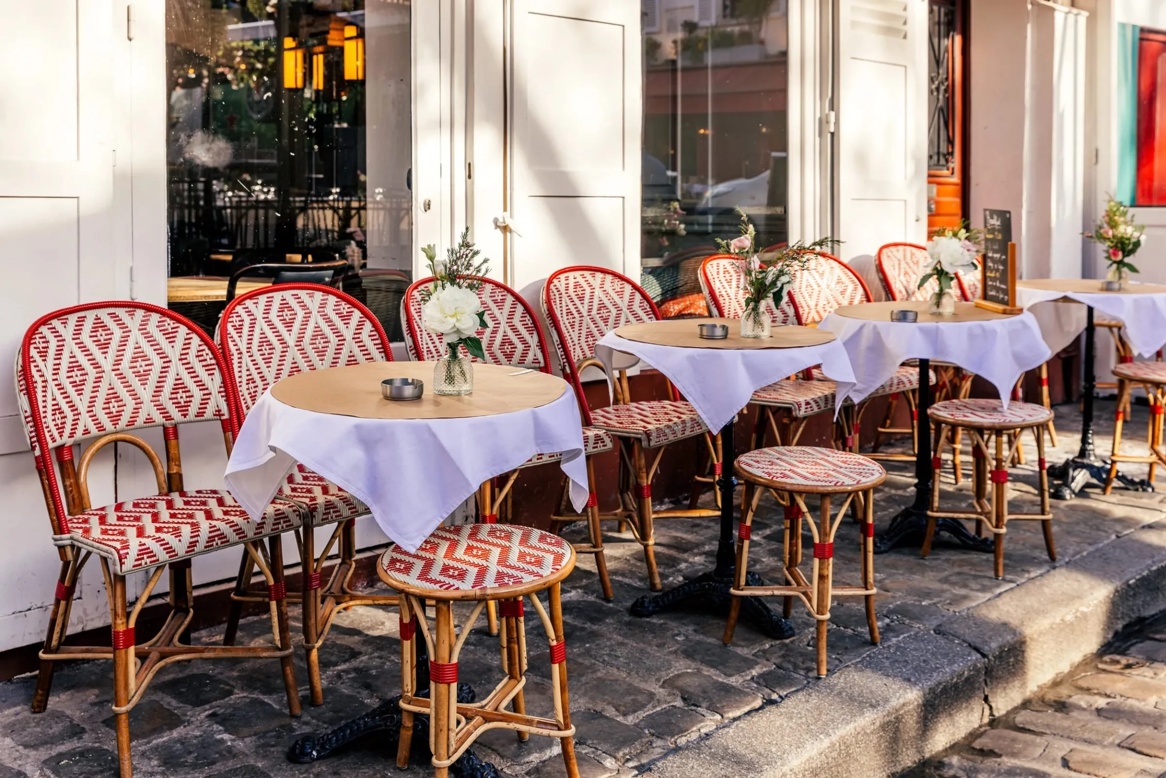 Parisian outdoor cafe seating with white tablecloths, red and white patterned chairs