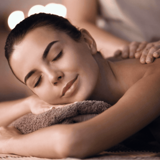 Young woman smiling peacefully while lying down with eyes closed, receiving a massage