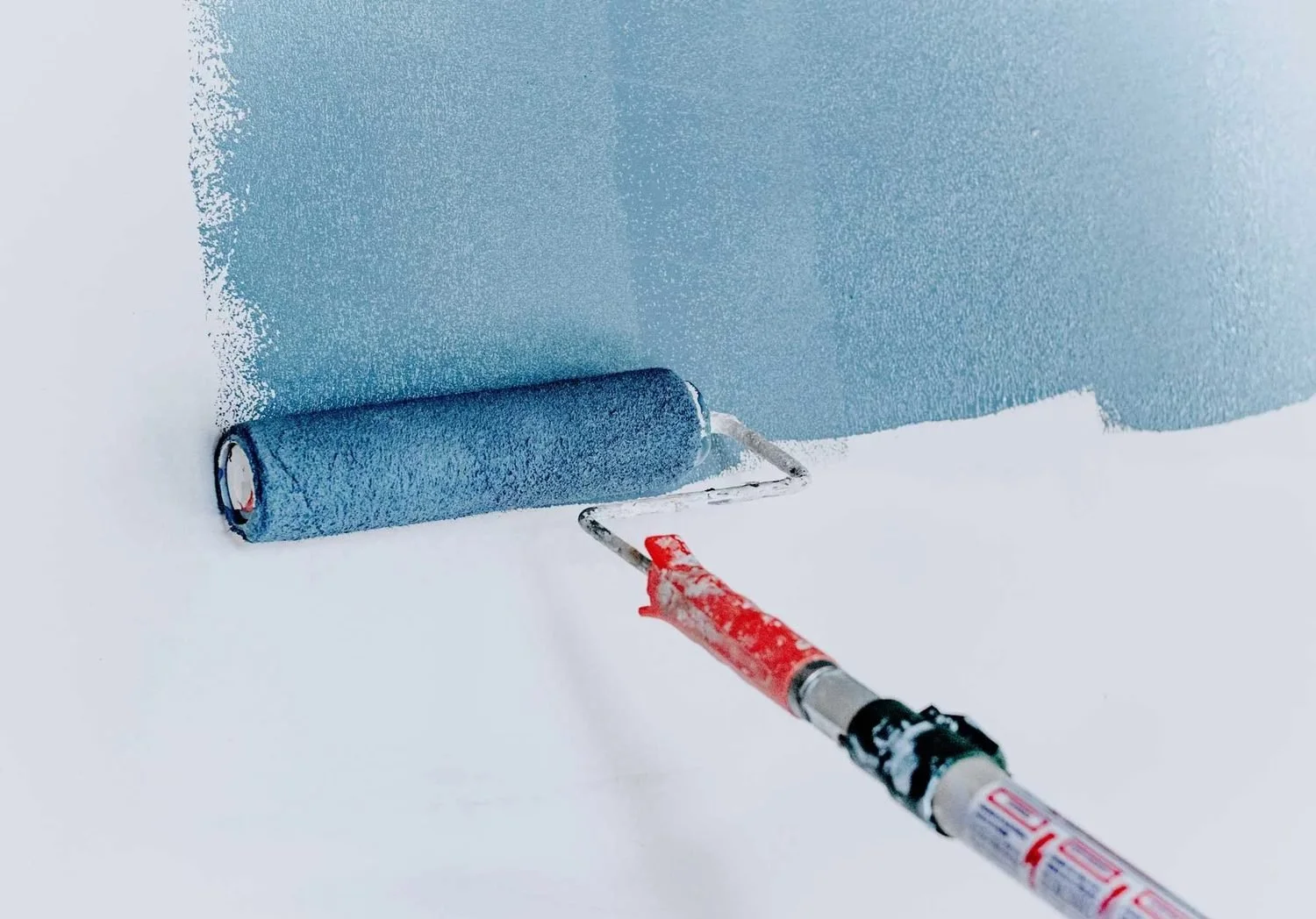 Paint roller applying blue paint to a wall