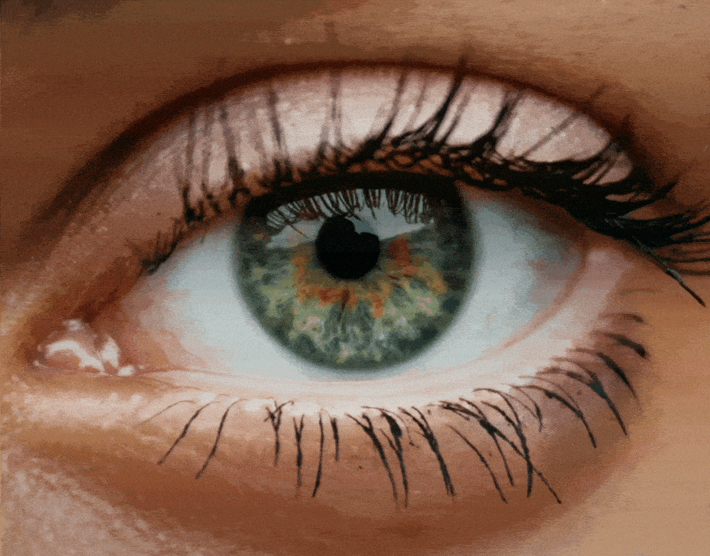 Close-up of a human eye with a blue-green iris, dark pupil, long eyelashes, and detailed reflections in the eye.