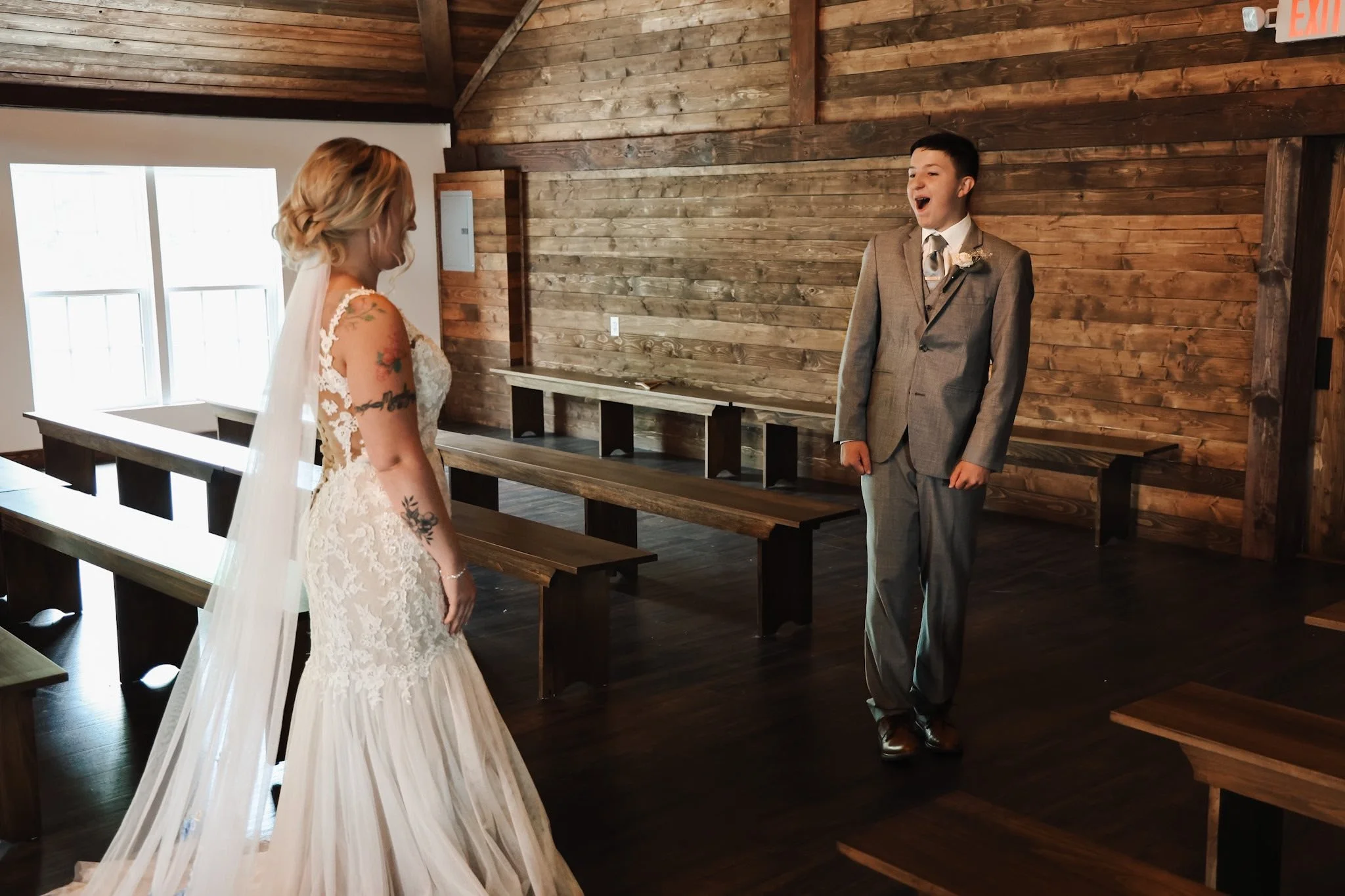 A bride and groom standing inside a wooden church, facing each other with smiles.