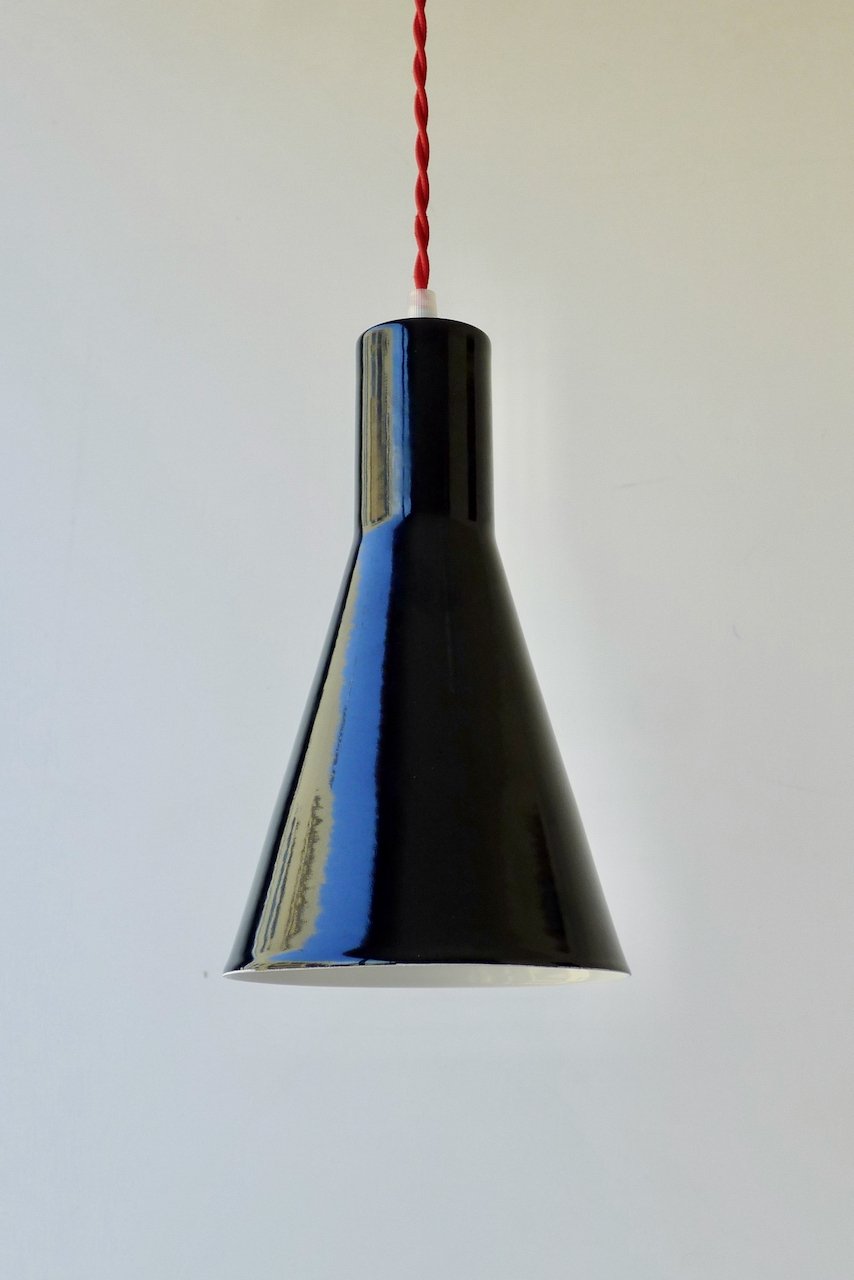 Black cone-shaped pendant light hanging from a red twisted cord against a white background.