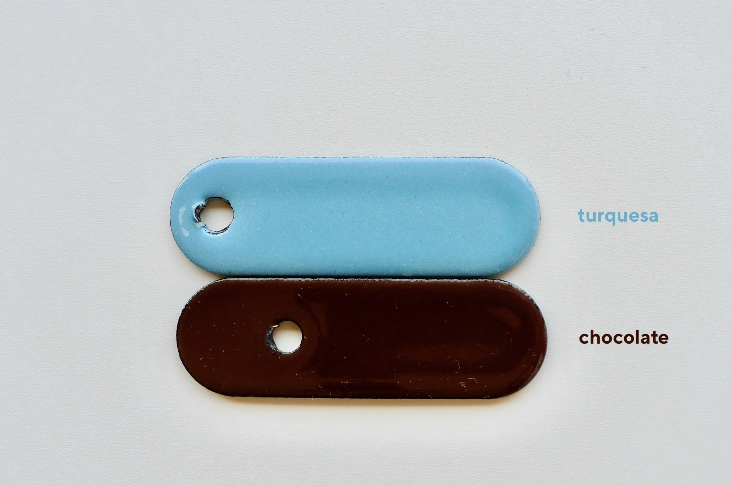 Two rectangular enamel samples placed in a vertical row on a white surface, with labels indicating their colors as turquoise and chocolate.