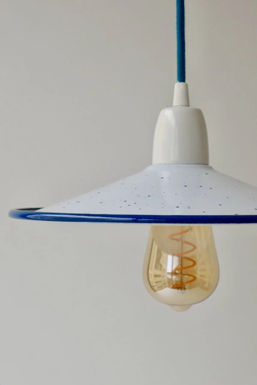 Close-up of a hanging white pendant light with a blue cord and visible filament bulb