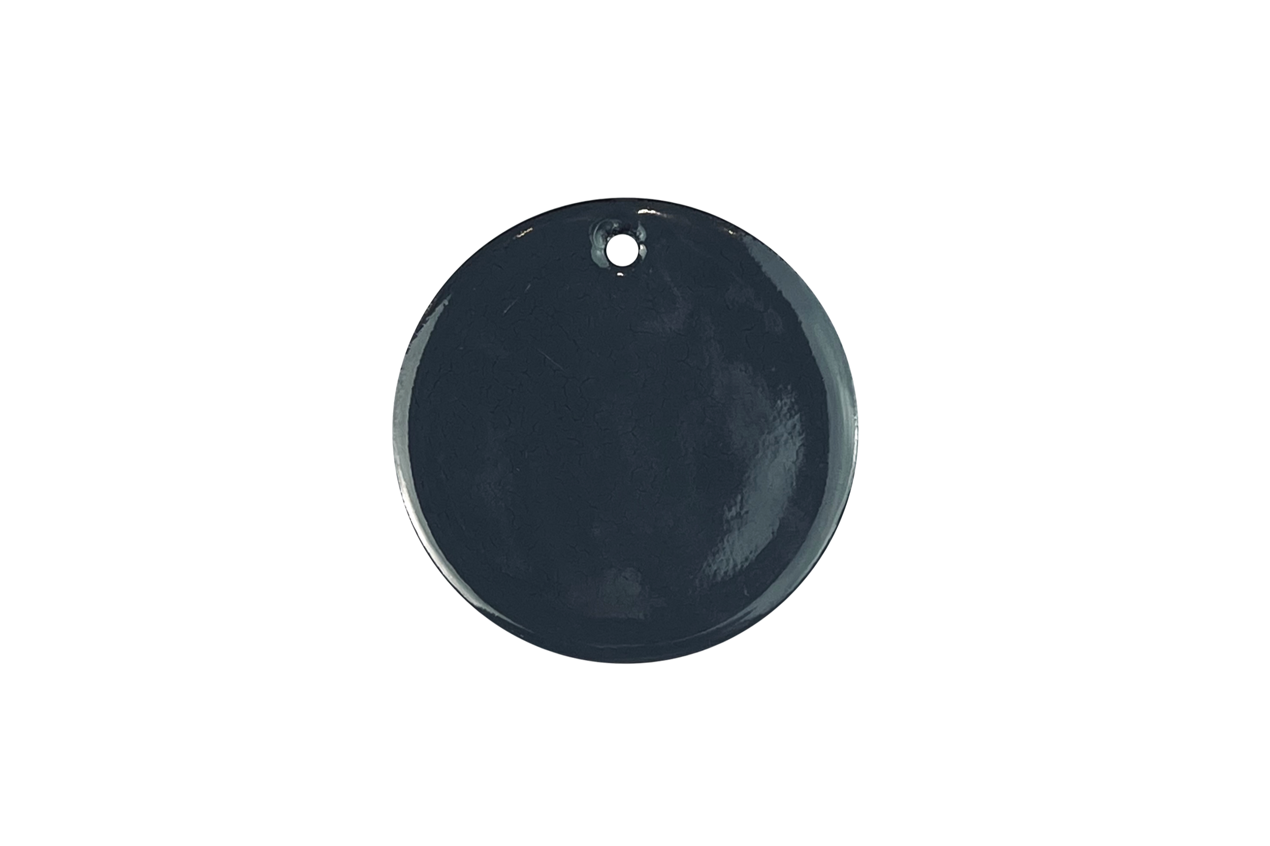 Close-up of a dark-grey circular enamel sample with a small hole near the top, set against a white background.