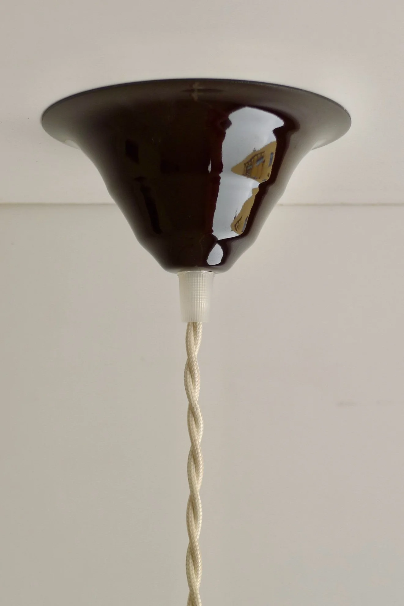 Chocolate brown enamel canopy, against a light ceiling, hanging with a beige twisted cord.