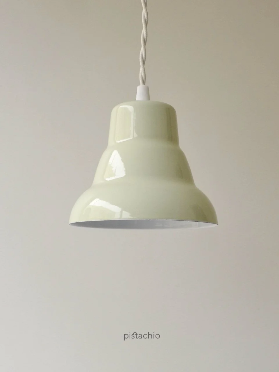 A pistachio-colored pendant light fixture with a white cord. The light has a rounded, bell-shaped shade with a glossy finish. The word "pistachio" is printed at the bottom of the image.
