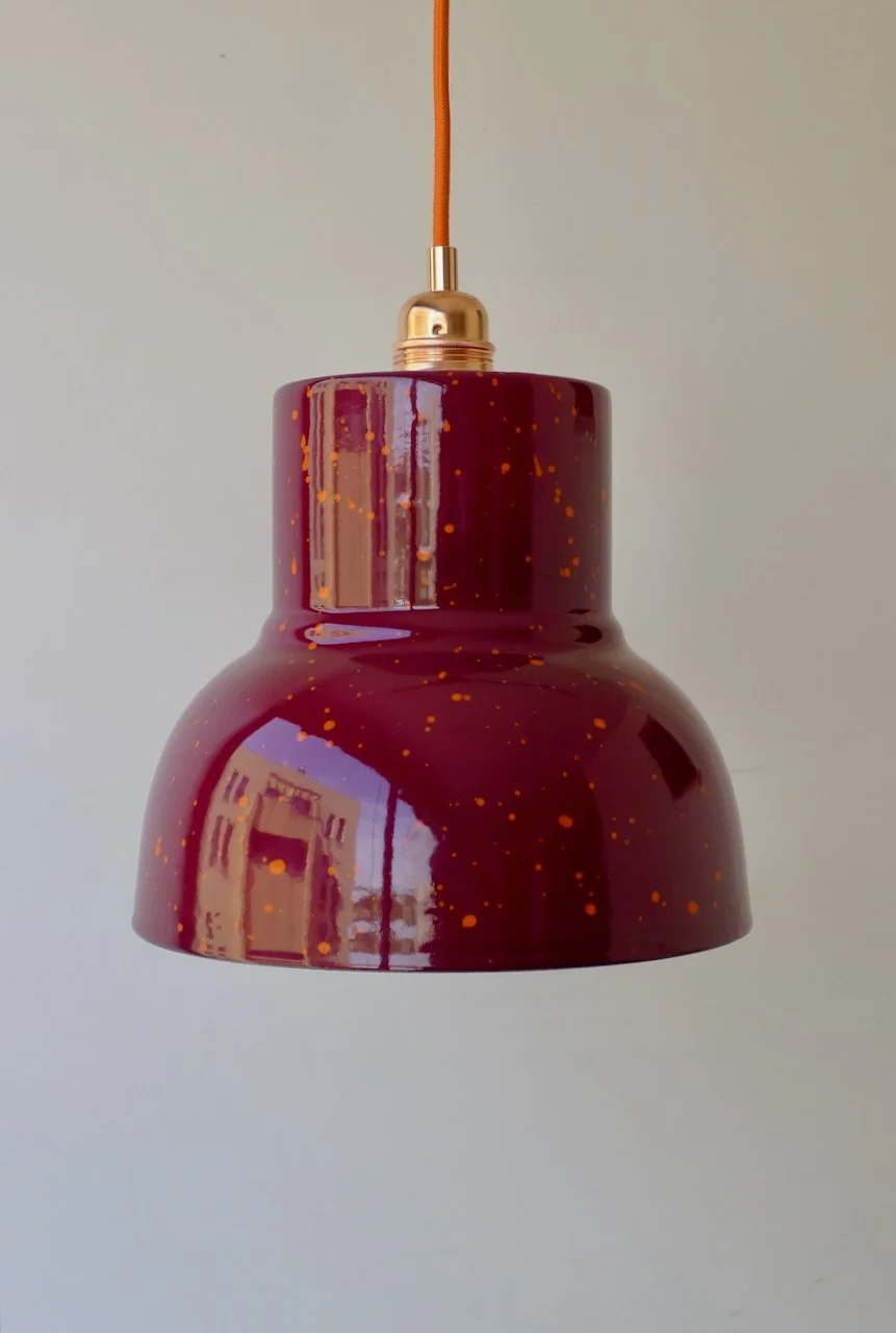 Burgundy pendant lamp with orange speckles hanging from an orange cord
