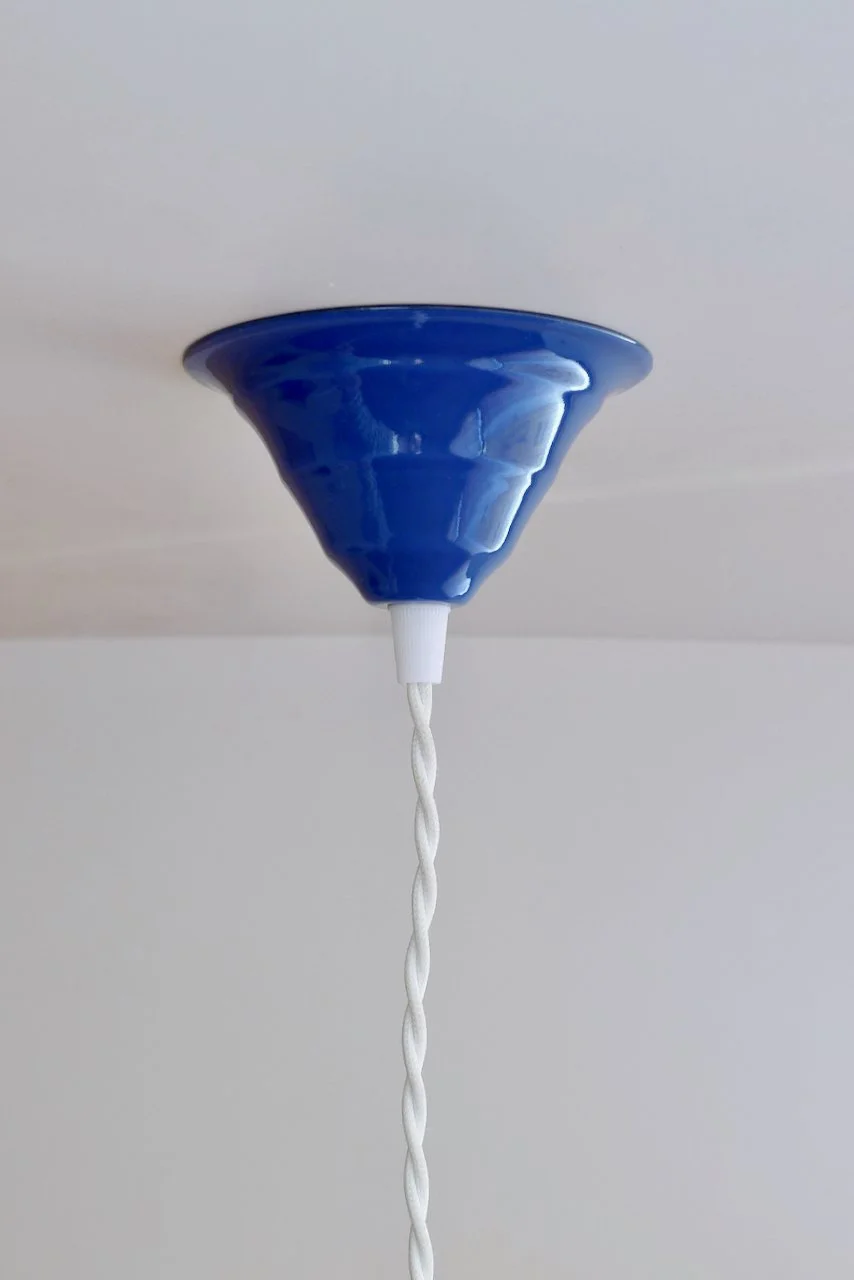 Blue ceiling light fixture with a white twisted cord hanging down.