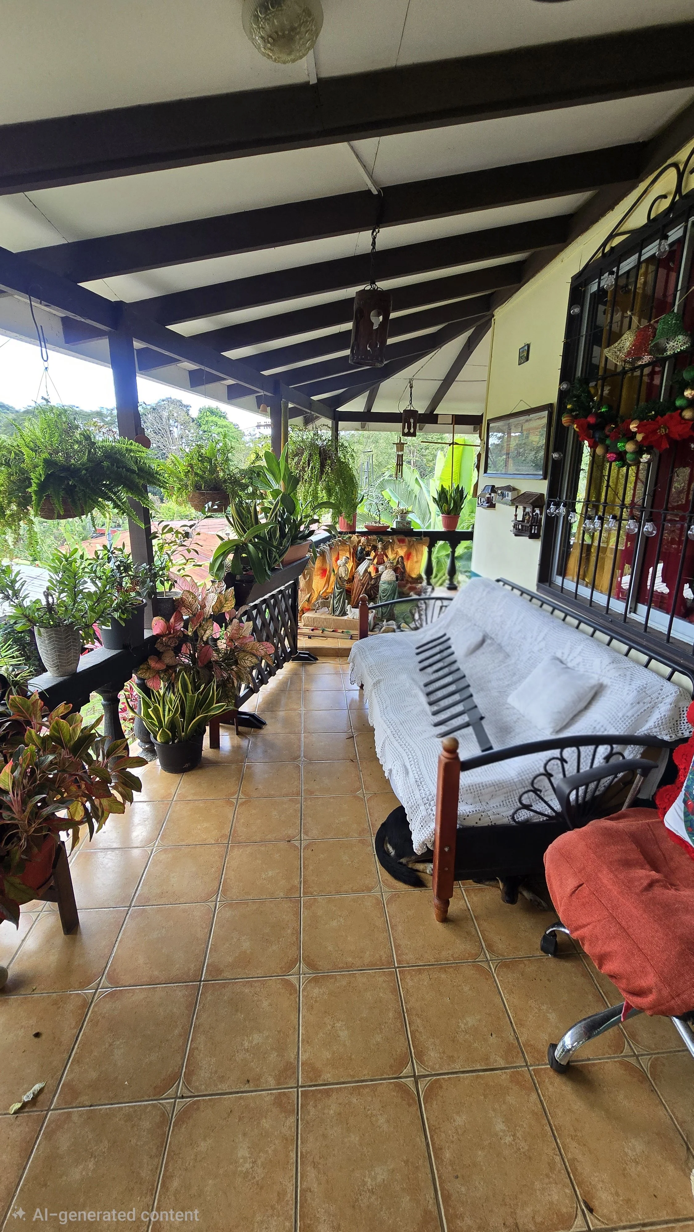 A decorated balcony with potted plants, a nativity scene, and Christmas decorations. It has a tiled floor, a white cushioned bench, and a window with bars and holiday decor.
