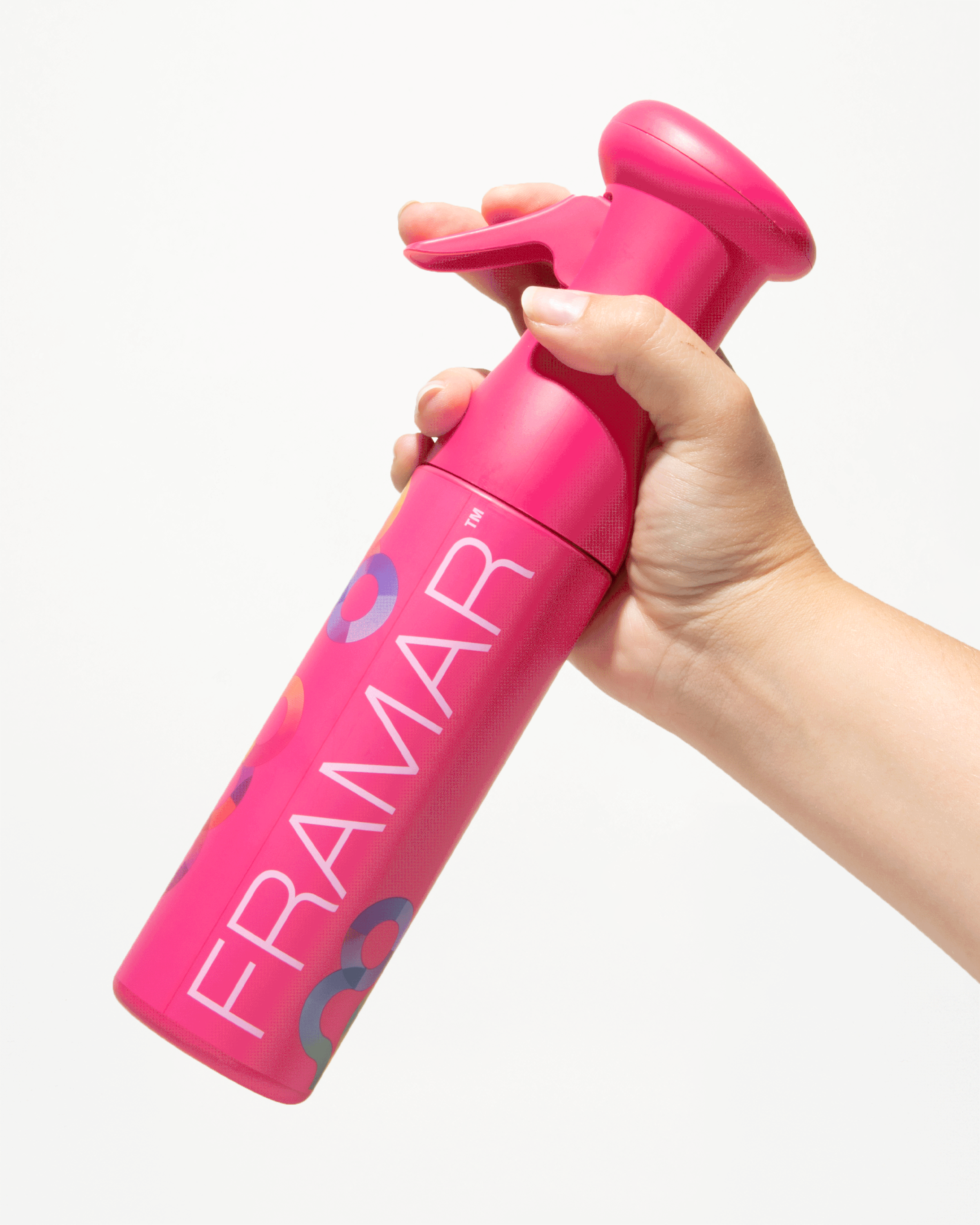 A hand holding a pink spray bottle with a bubblegum pink nozzle, and the word 'FRAMAP' written on it along with colorful circles.